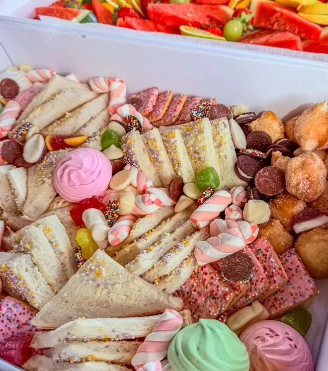 Assorted sweet treats including mini sandwiches, cookies, candy canes, marshmallows, and colorful mini cupcakes or pastries.