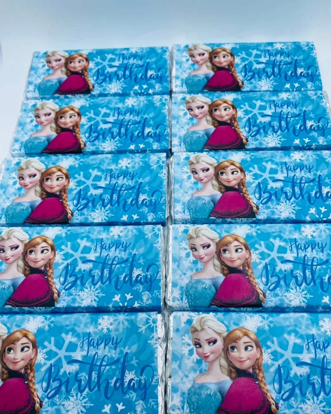 Multiple frozen-themed birthday gift boxes with Elsa and Anna from Disney's Frozen, decorated with snowflakes and 'Happy Birthday' written on them.