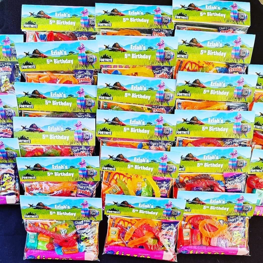 Multiple packs of candy with a Fortnite-themed birthday party favor design featuring a llama, a helicopter, and green grass, celebrating Eziah's 5th birthday.