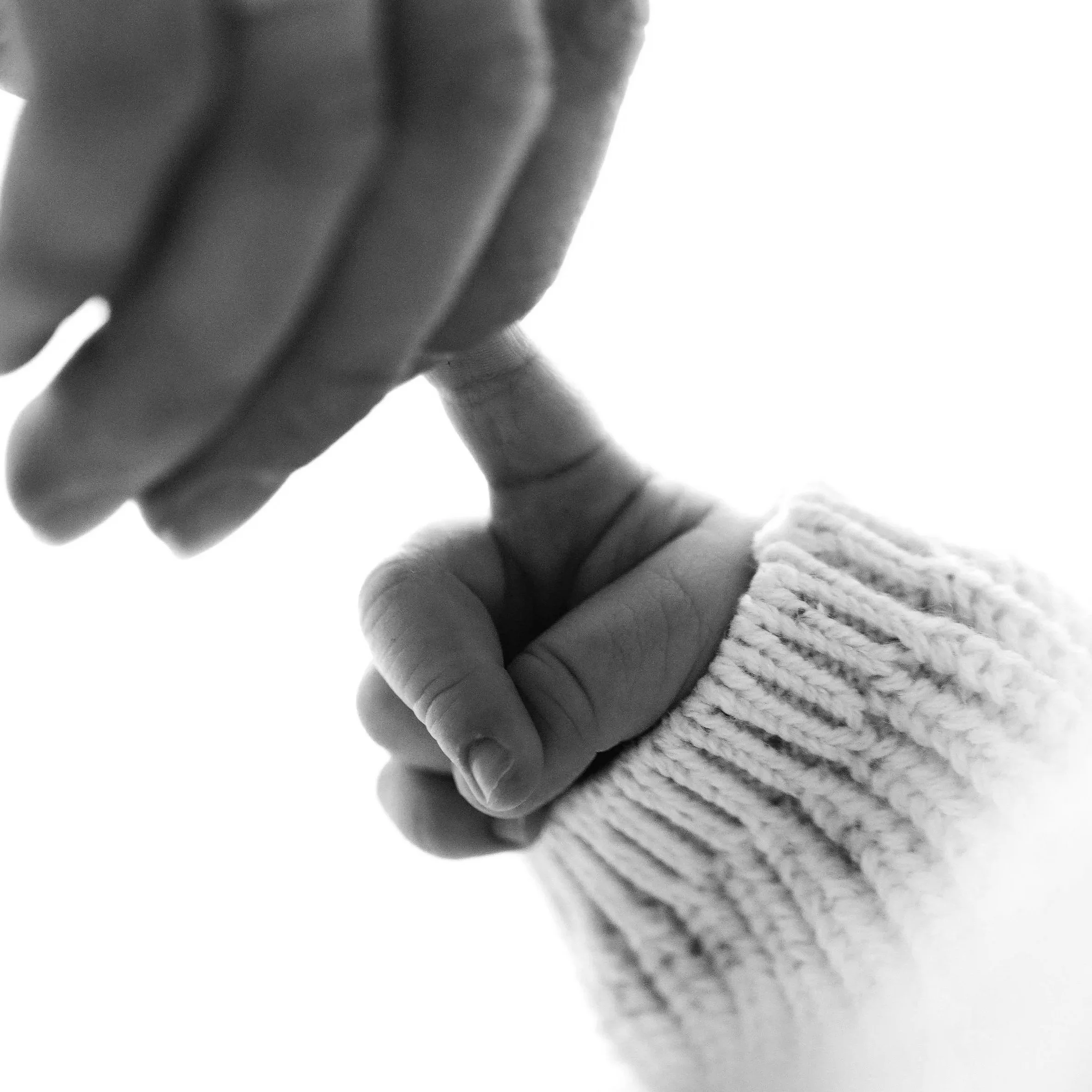Close-up of a person's hand with fingers touching a textured surface, black and white photograph.