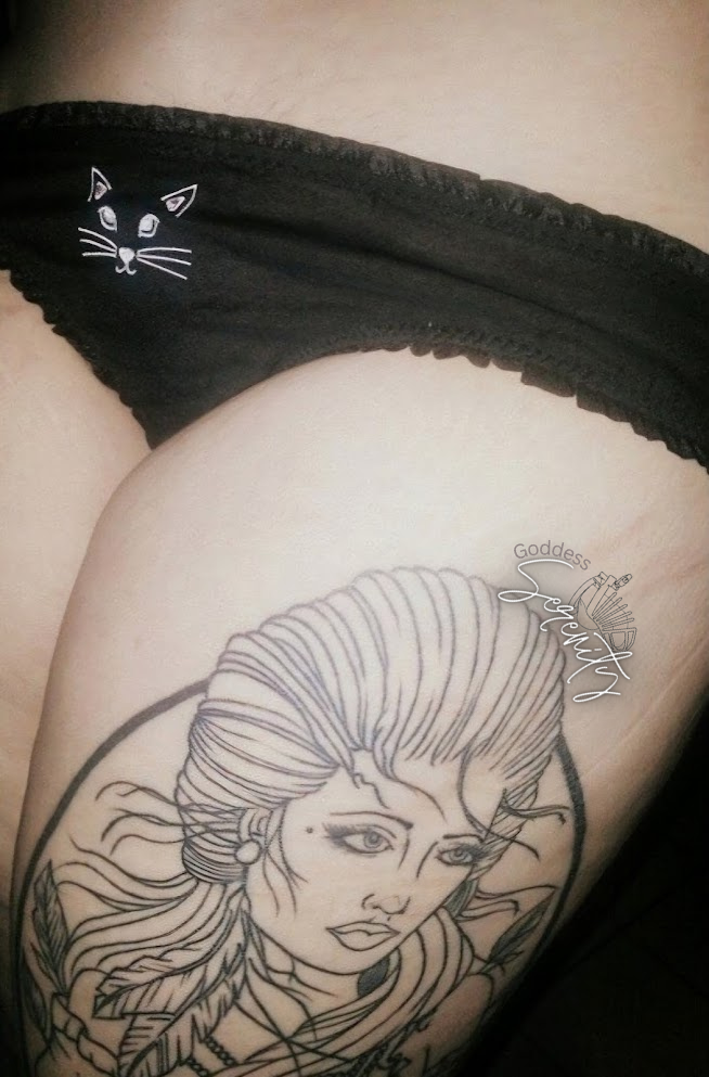 Tattoo of a woman with feathers in her hair and a halo, with the word 'Goddess' written in cursive next to her.