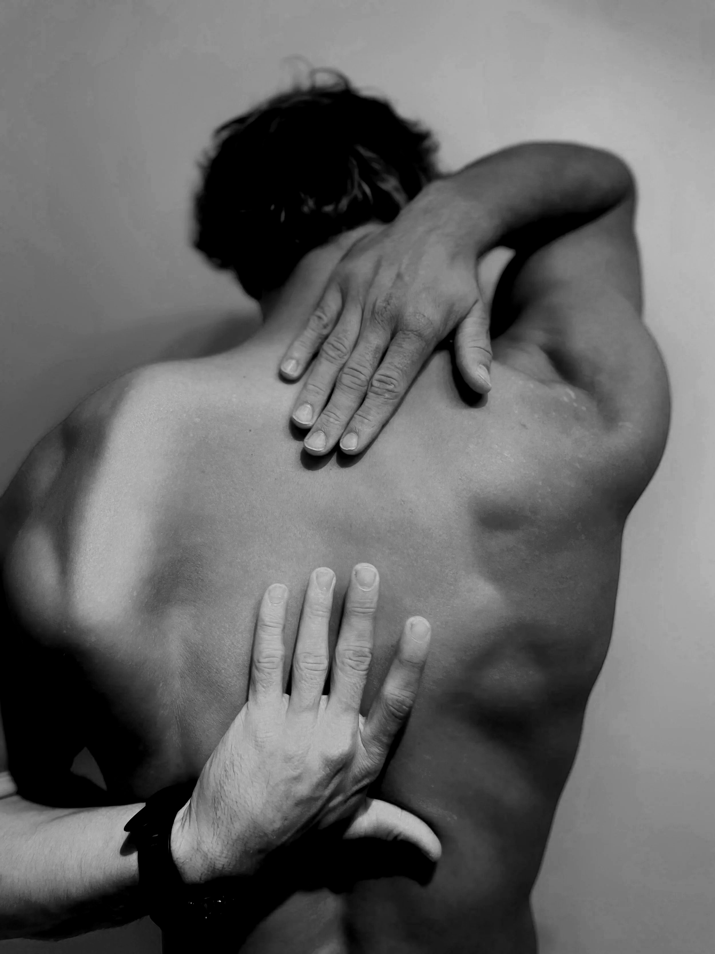 Black and white photograph of hands placed on a person's body, capturing a massage or relaxing touch.