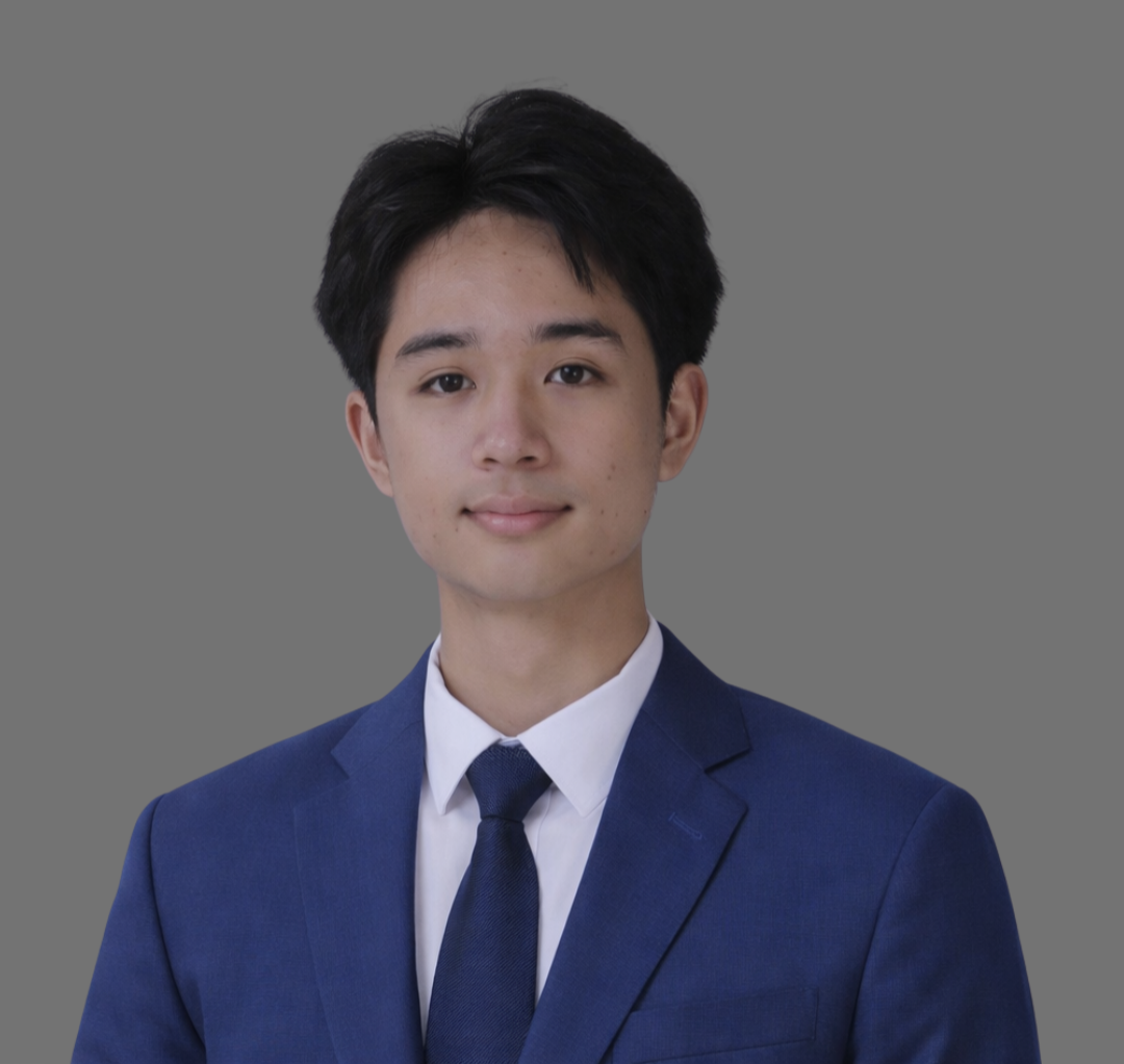 Young man in a blue suit and white shirt, wearing a dark blue tie, against a gray background.