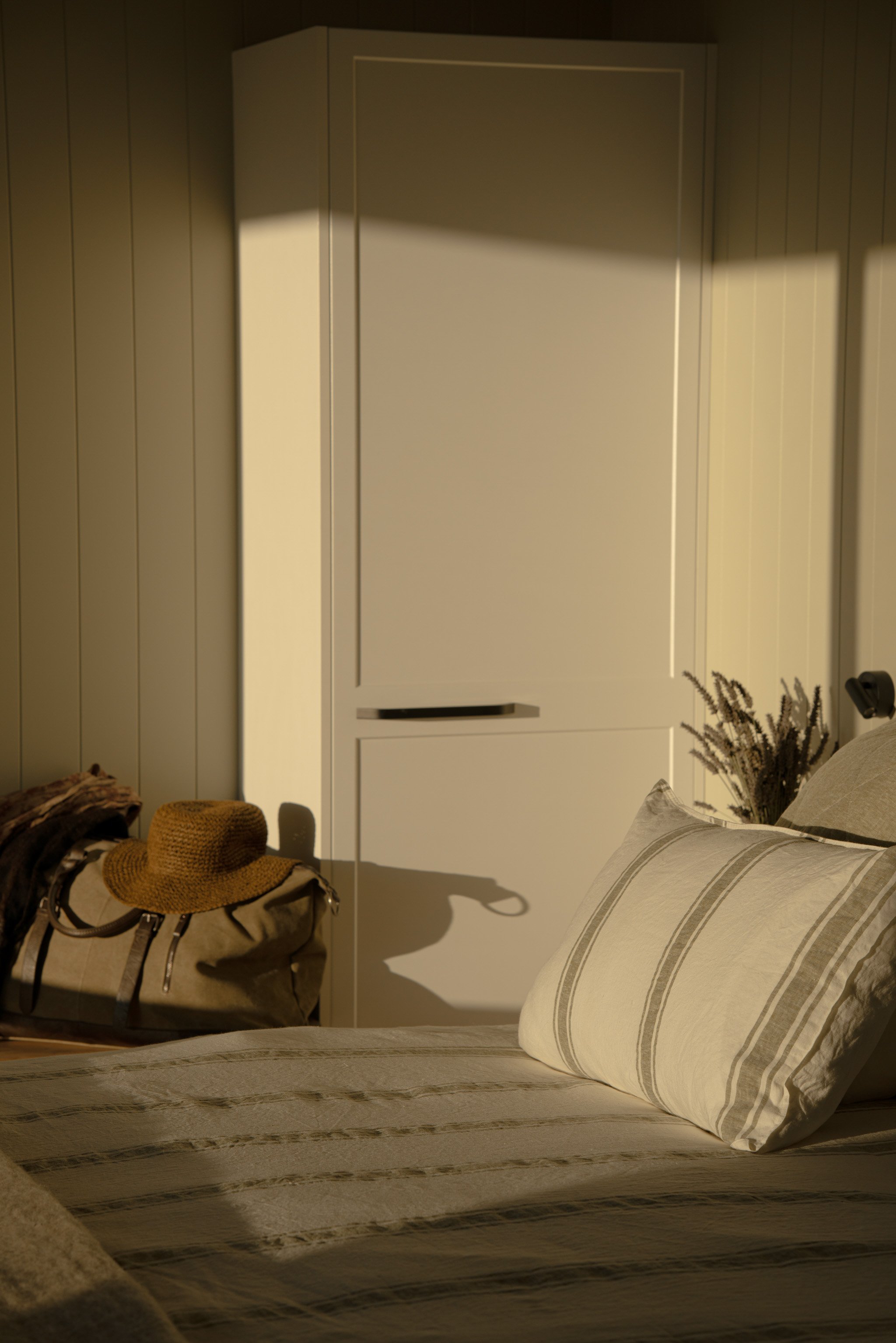 Linen bedding and woven hat on travel bag in Maunga Tipu studio, evoking slow travel and unhurried retreat in Fiordland