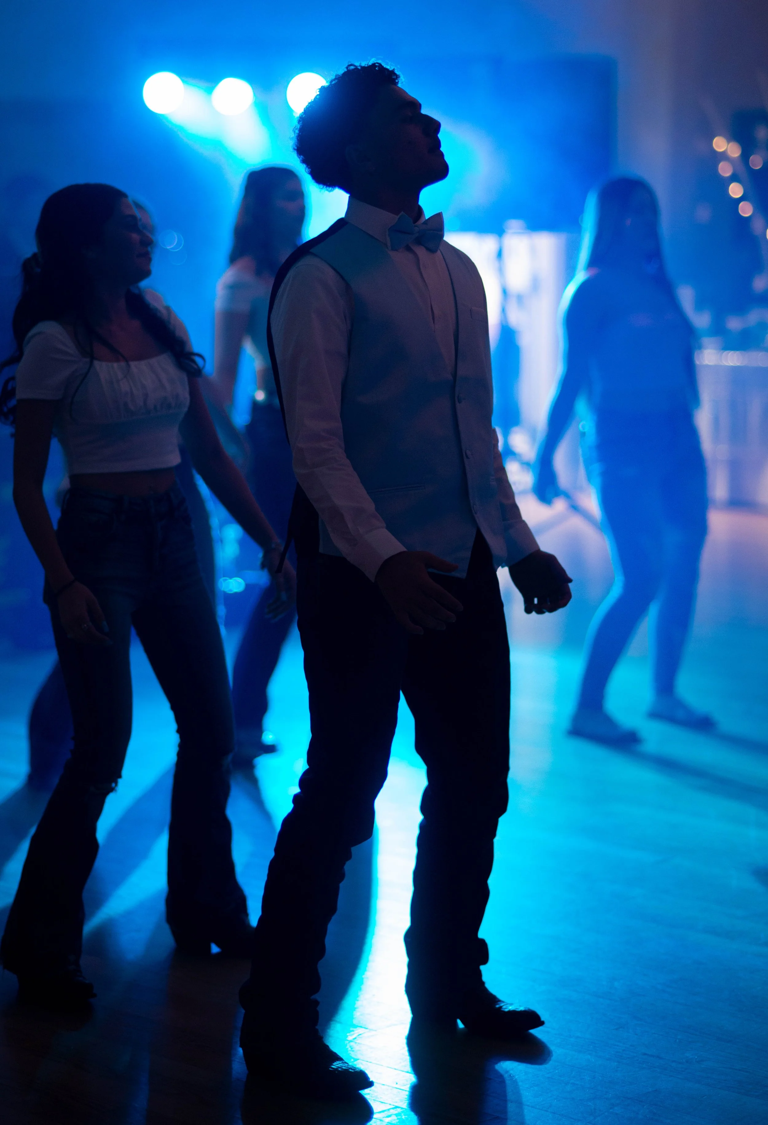 People dancing at a party or nightclub with blue lighting.