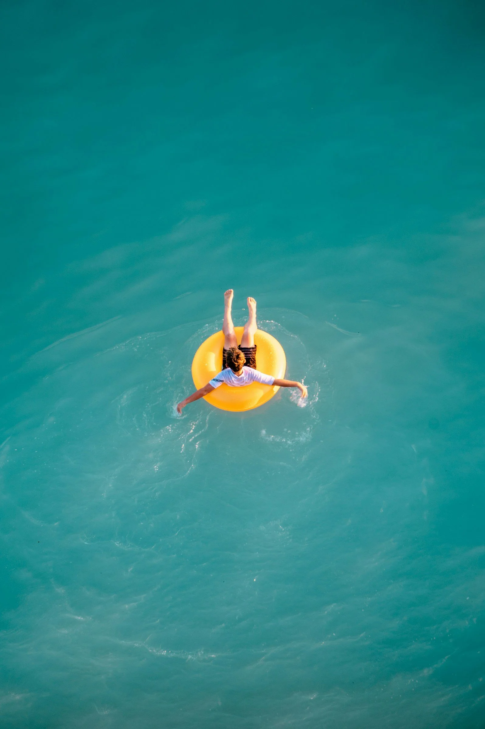 Person floating on an orange pool float in a large body of water.