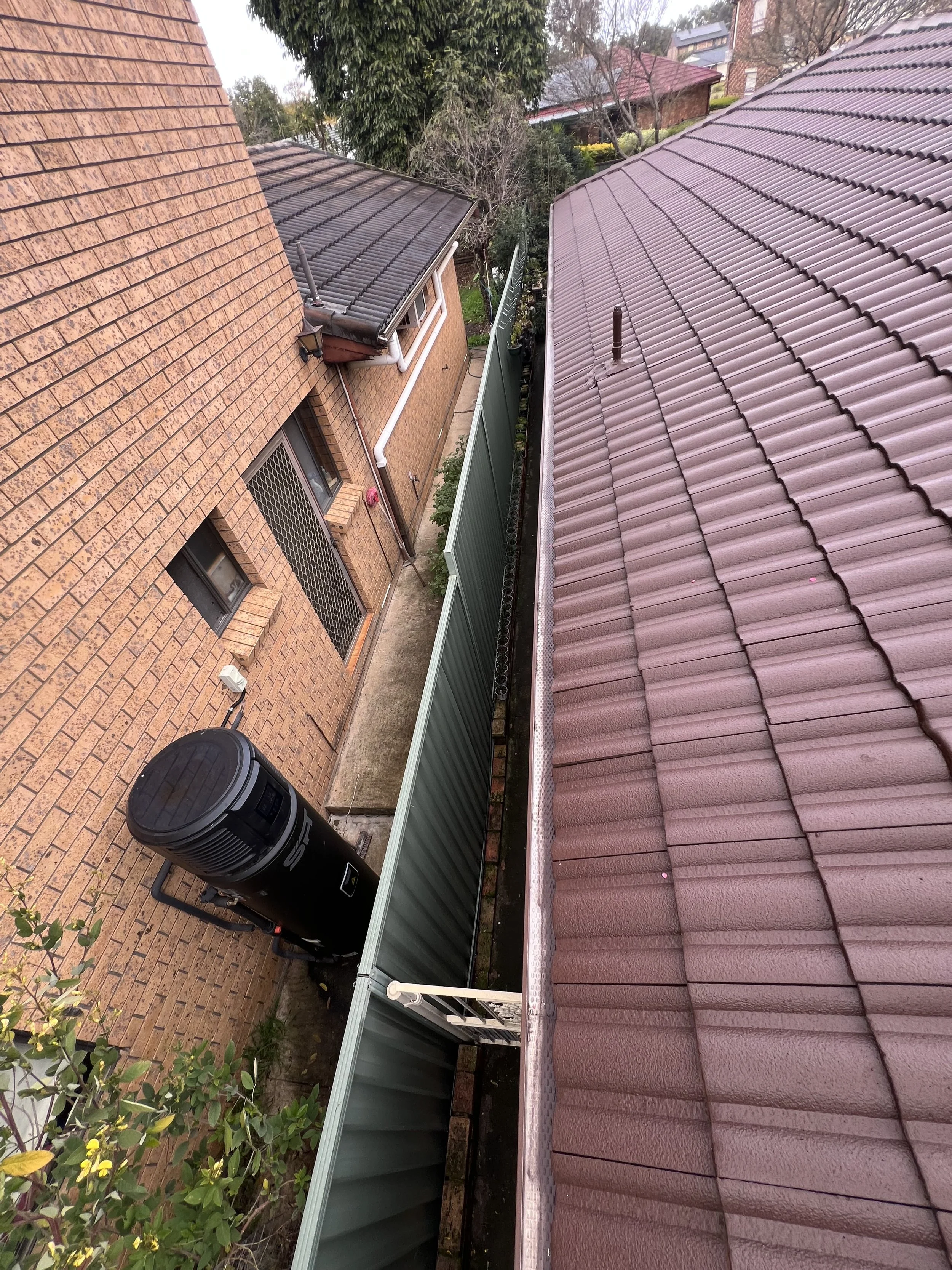 View of rooftops, a brick house, and surrounding greenery on a cloudy day.