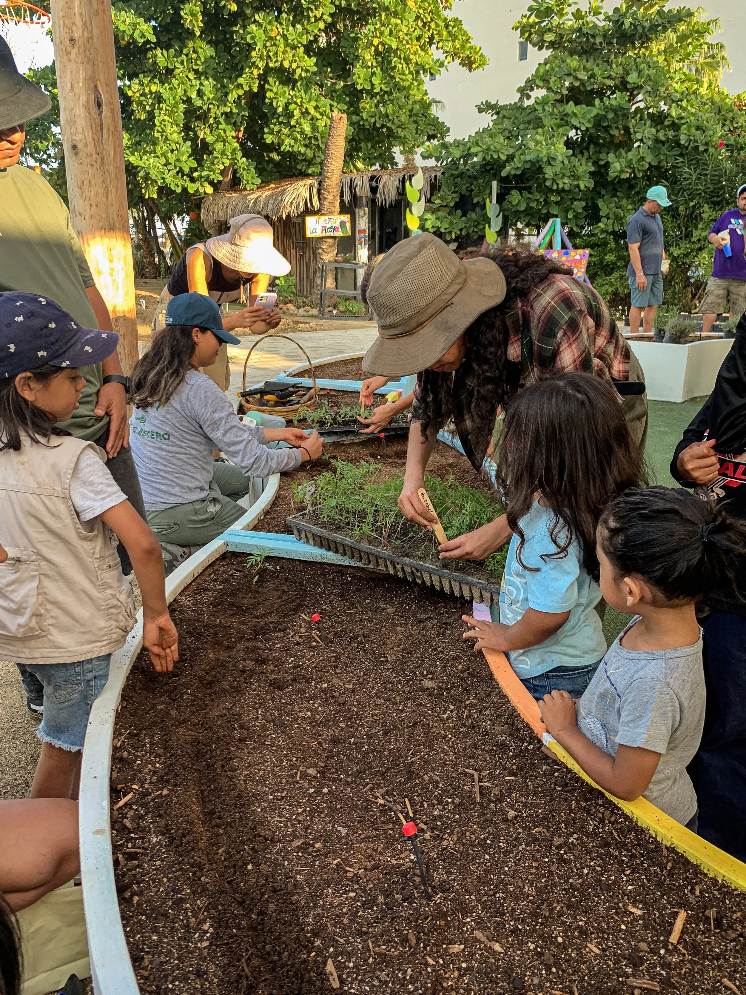 Niños y adultos trabajando la tierra en un huerto.