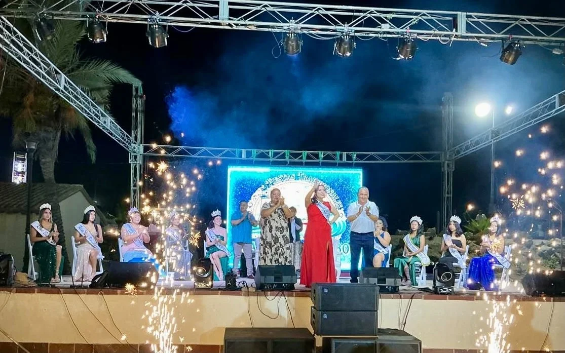 Gente en un escenario durante una ceremonia o evento con fuegos artificiales y una pantalla de fondo con logotipo.