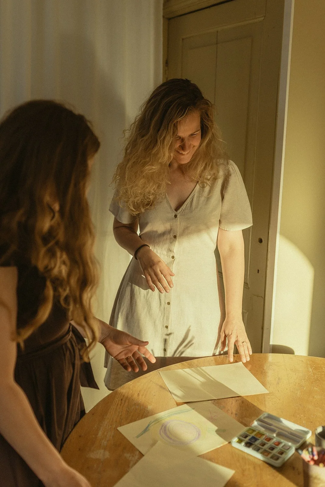 Twee vrouwen bespreken tekeningen op een tafel met tekenmateriaal.