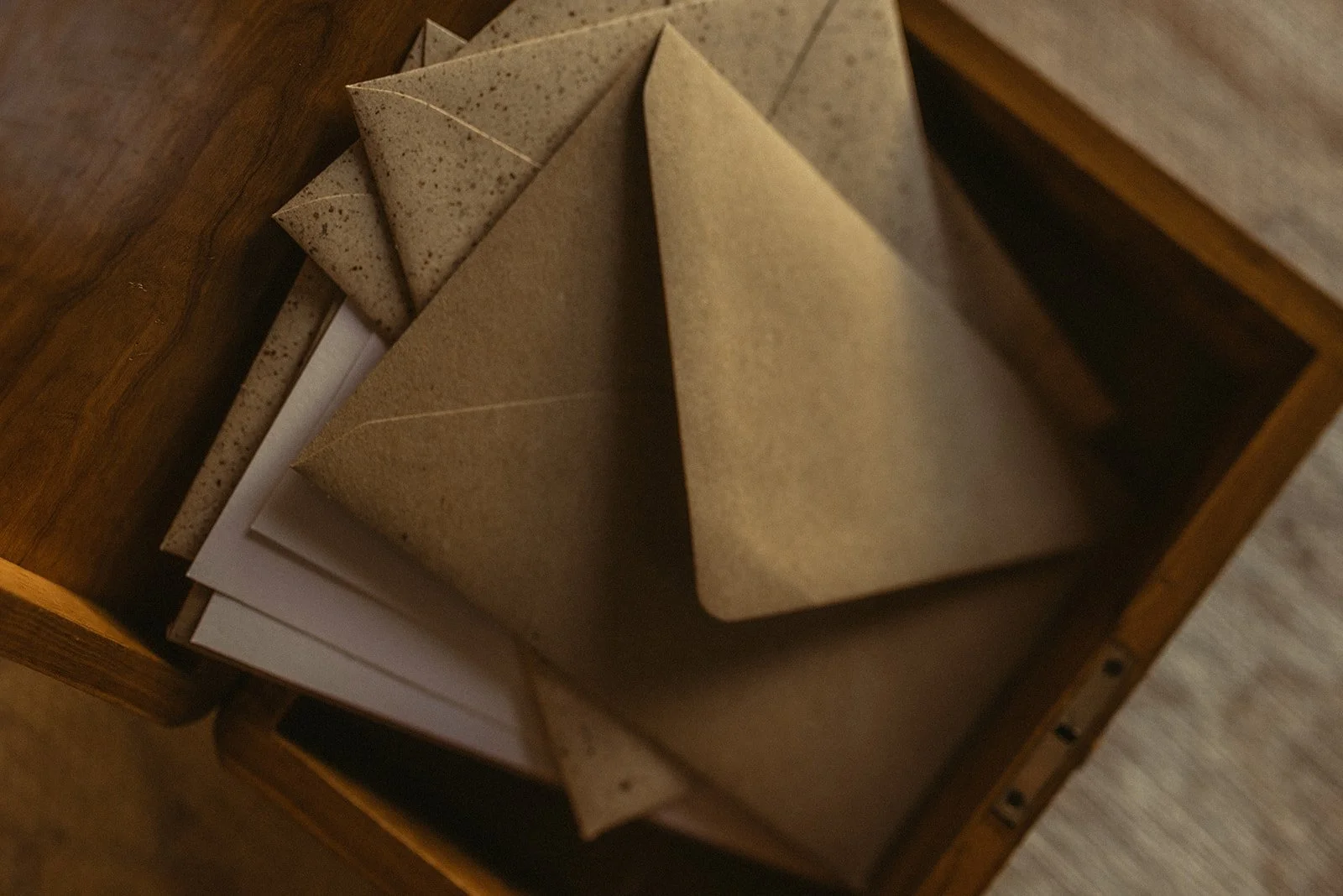 Verschillende enveloppen en postkaarten in een houten ladenkast.