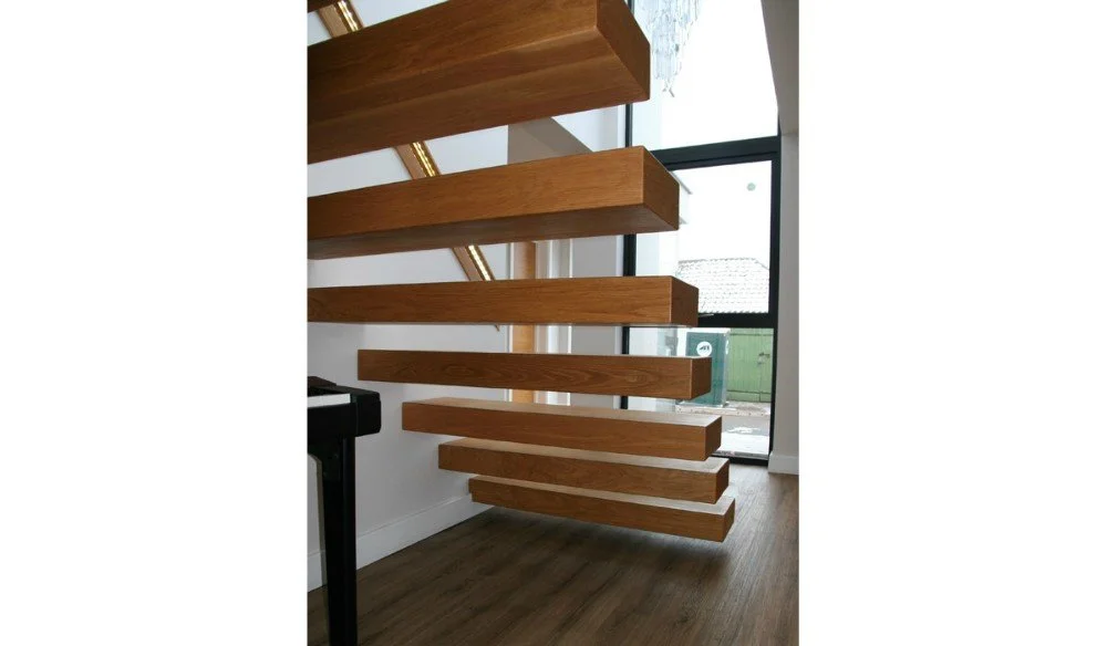 Indoor staircase with floating wooden steps and glass railing in a modern home.