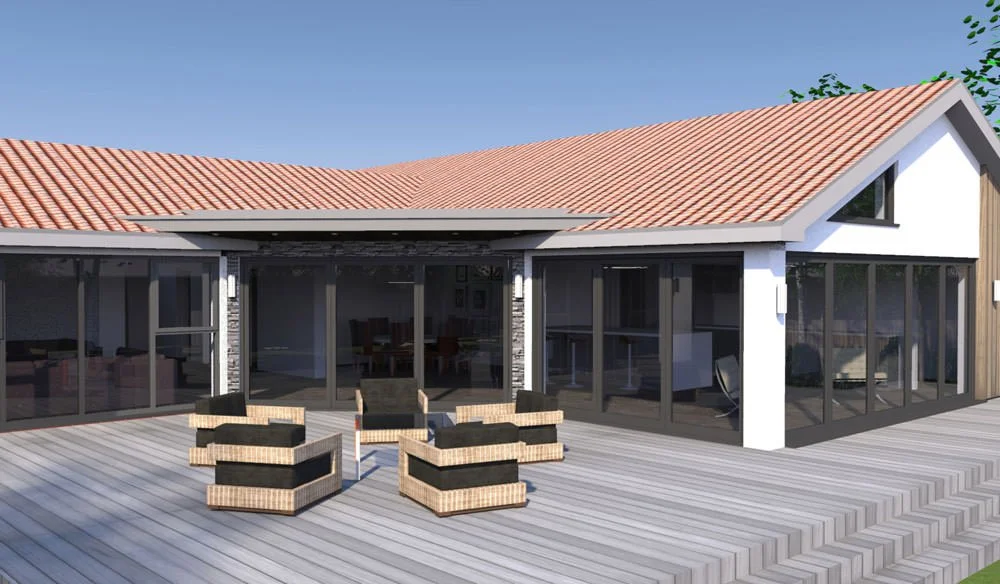 A modern house with a red-tiled roof and large glass sliding doors on a wooden deck, with four outdoor wicker chairs arranged in a circle.