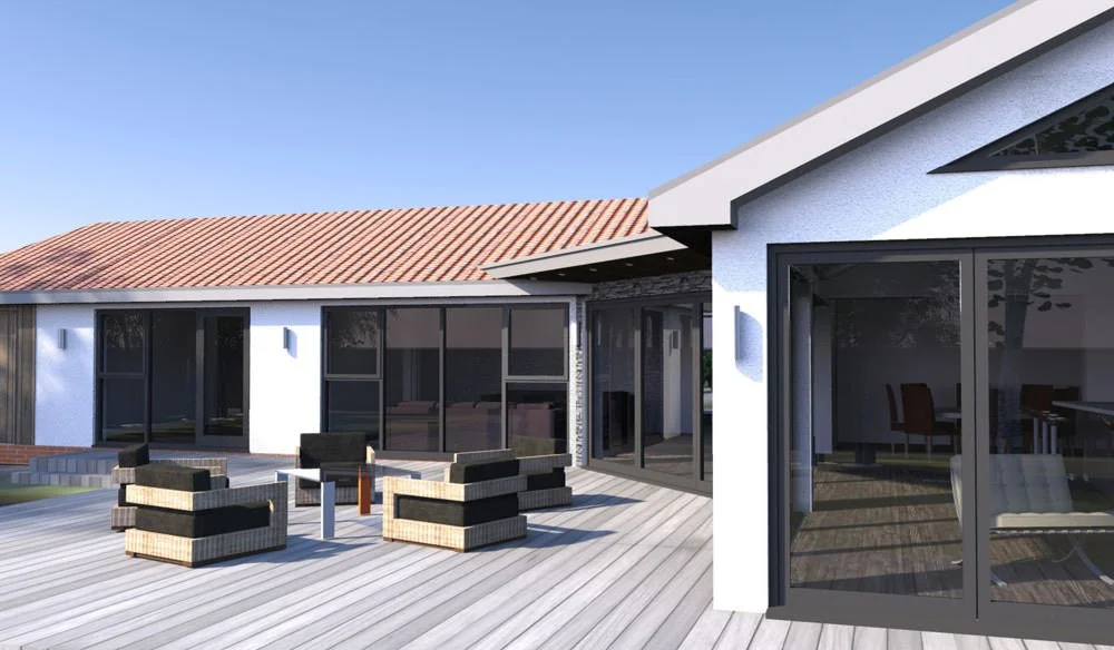 A modern house with a large wooden deck, black outdoor furniture, white walls, large sliding glass doors, and a sloped red tile roof.