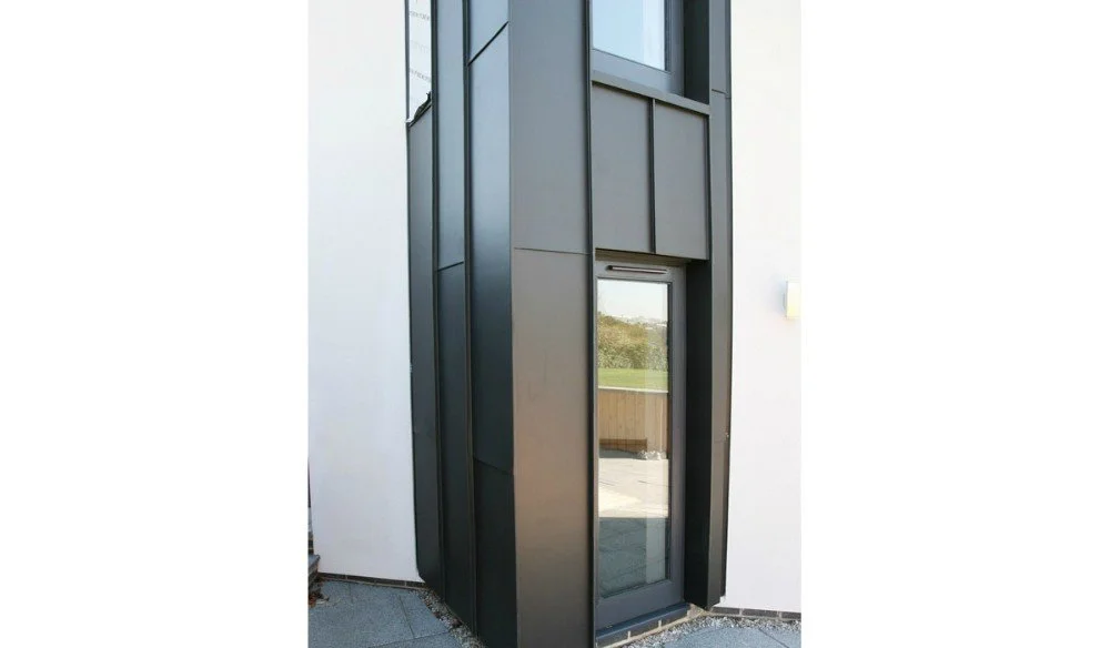 Modern exterior door with black frame and glass panel, set in a white building wall on an outdoor patio.