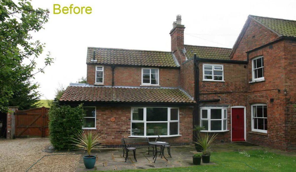 The image shows the back of a two-story brick house with white-framed windows and a red door. The yard is partly gravel and partly grass, with outdoor furniture including a table and chairs, and potted plants. "Before" is written in yellow text at th