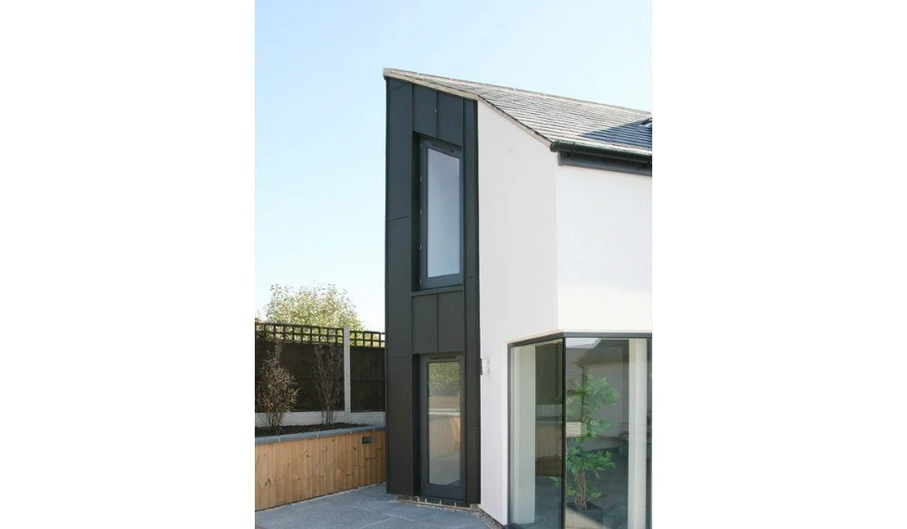 Modern two-story house with black and white exterior, large windows, and a sloped roof.