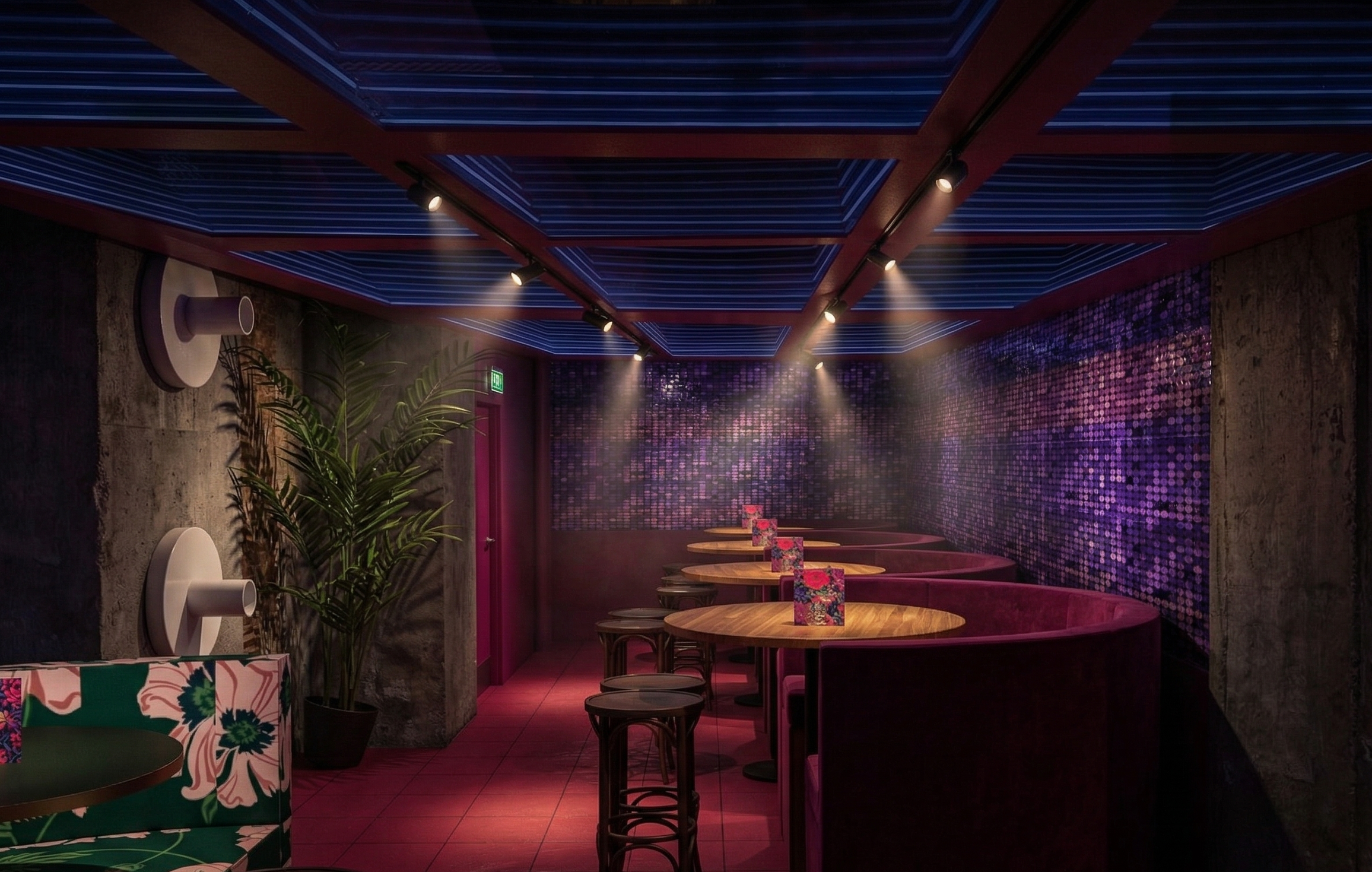 A dimly lit restaurant or lounge with round tables, pink velvet booths, and a purple mosaic wall. Spotlights shine on the ceiling, and potted plants add to the decor.