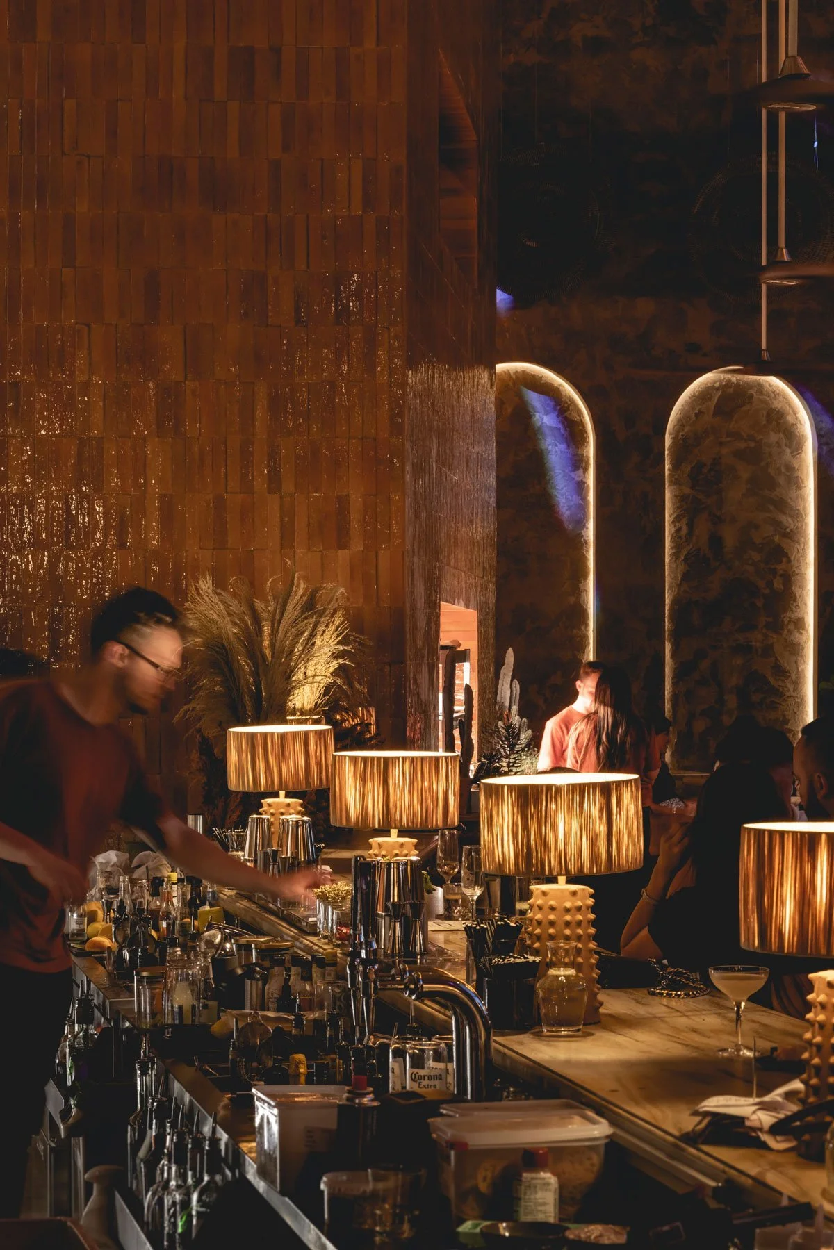 A dimly lit bar with warm lighting, modern decor, and patrons socializing.