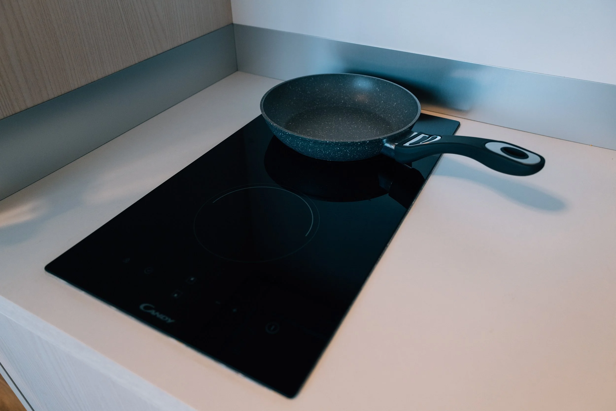 Padella di ferro con manico nero posizionata sulla piastra a induzione in una cucina moderna.