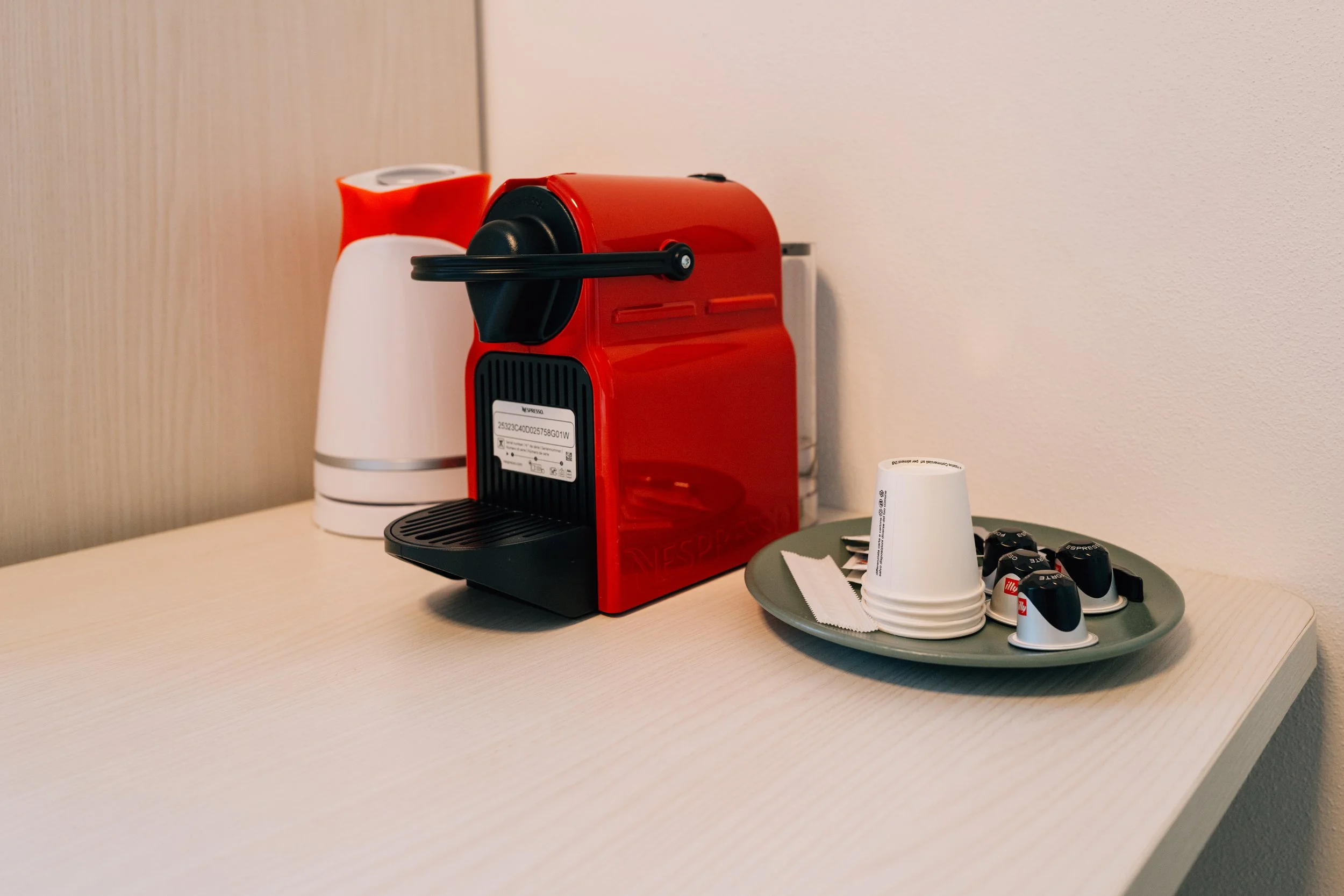 Macchina da caffè espresso rossa su tavolo con tazzine e bustine di zucchero