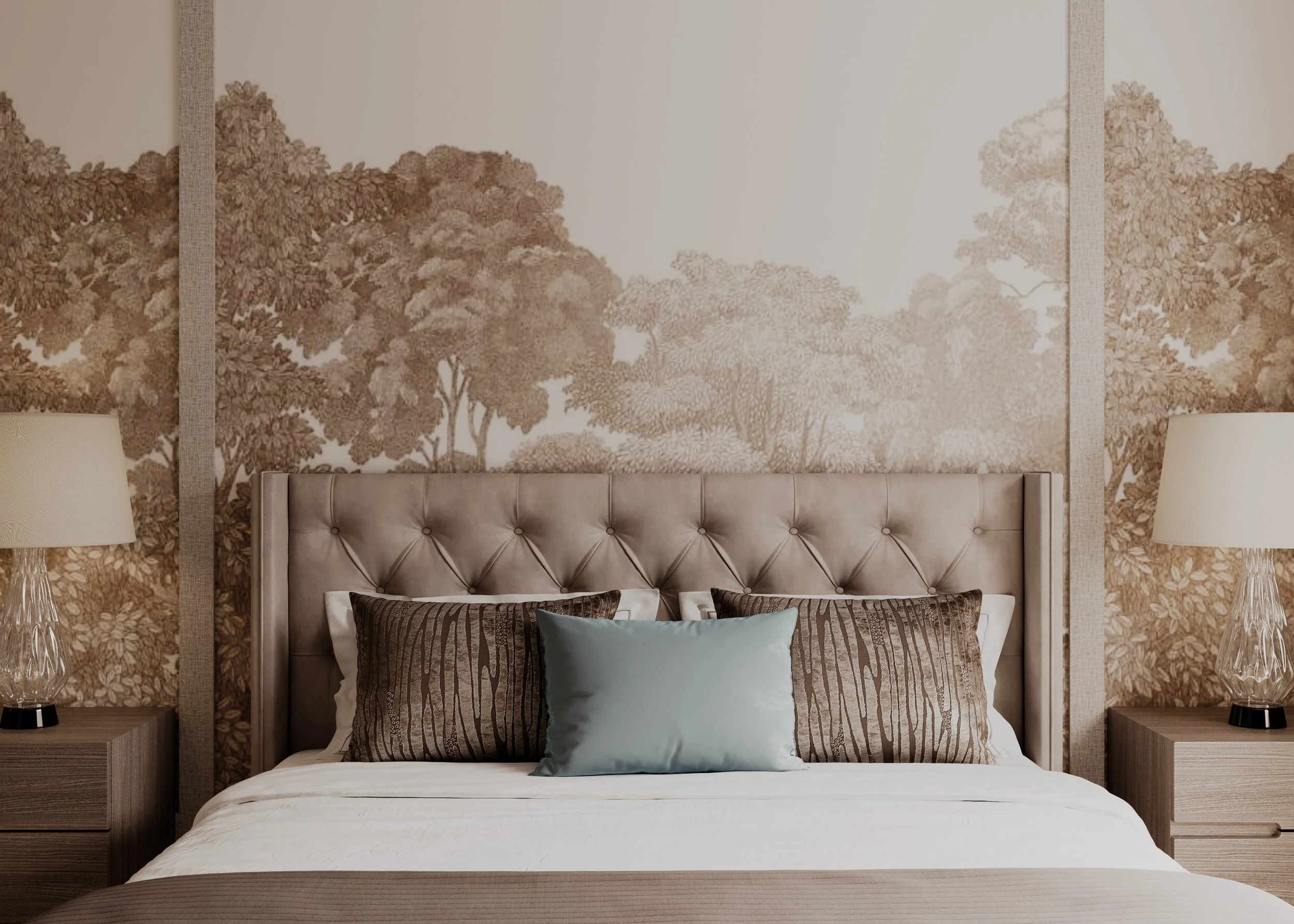 A bedroom with a beige upholstered headboard, decorative pillows, and a patterned wallpaper featuring trees in muted brown tones. Two matching bedside tables with lamps are positioned on either side.