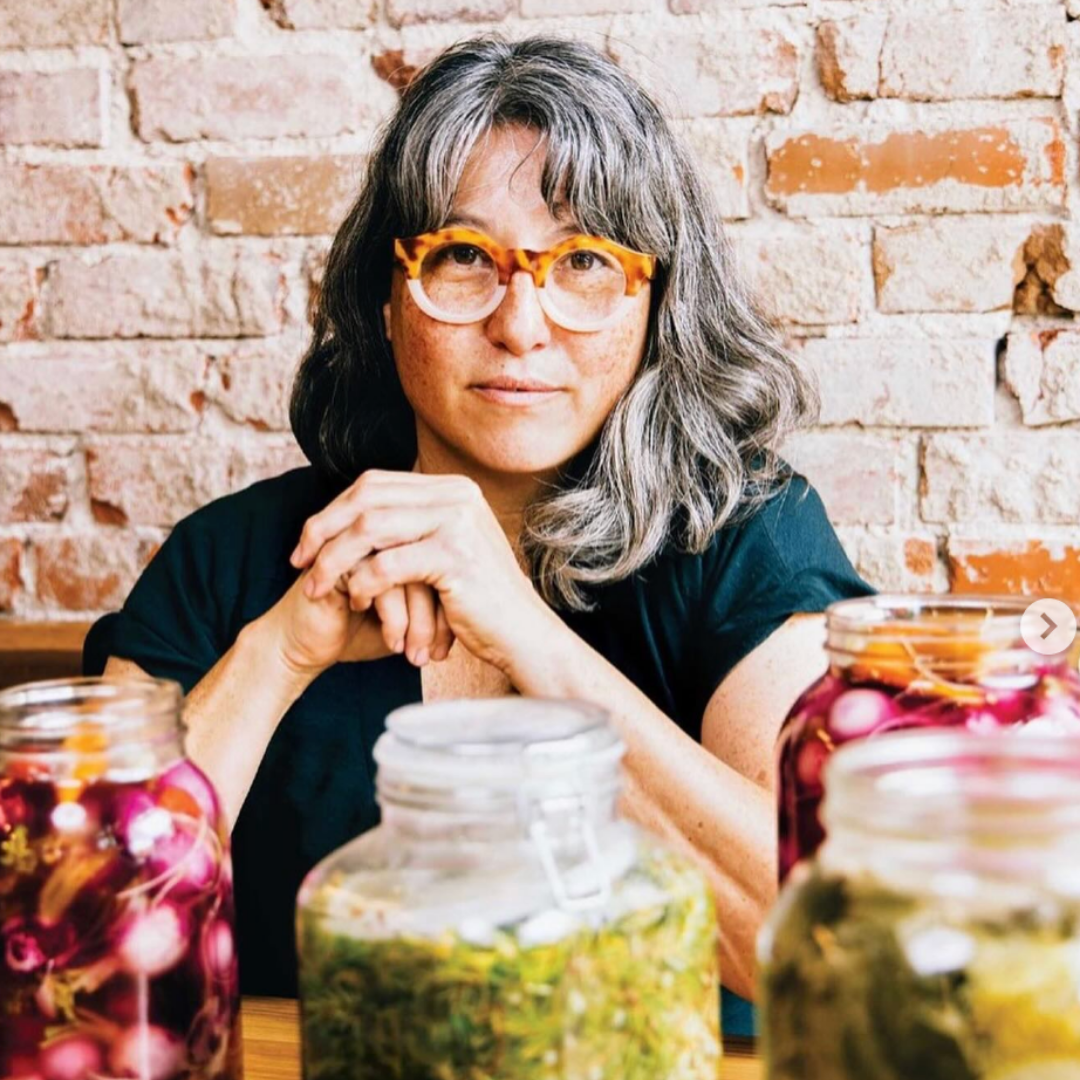 Fermentation practitioner, Mara Jane King, with jars of preserved vegetables, showcasing colourful ferments and food preservation techniques