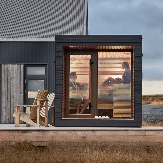 Black modular outdoor sauna with timber-lined in a Sussex garden.