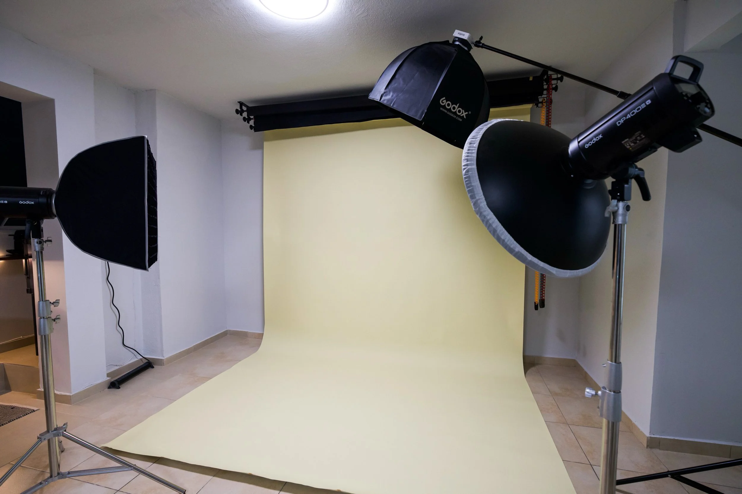 Photography studio setup with a yellow backdrop, studio lights, and softboxes.