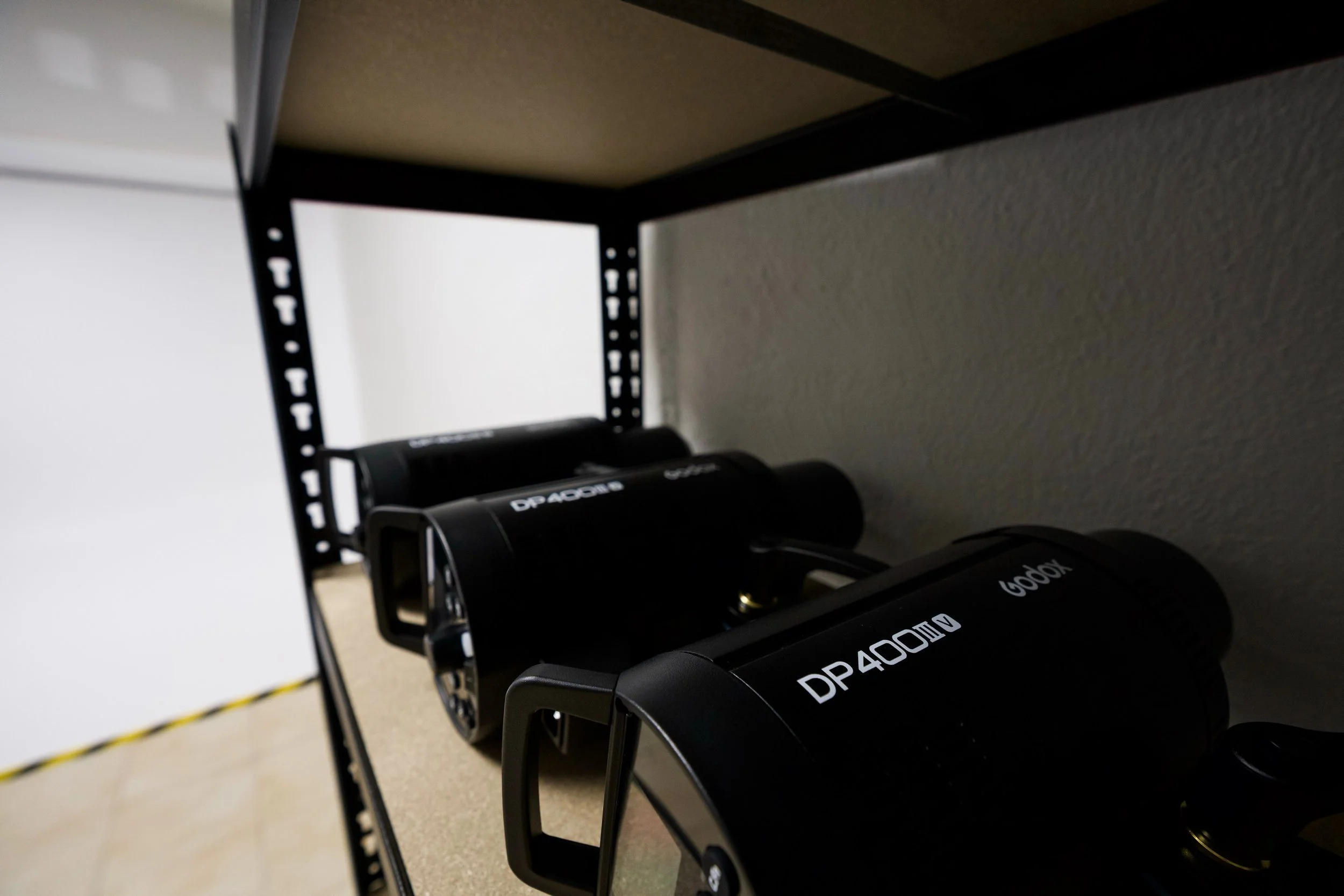 Close-up of a black fitness equipment with the label 'DP 4000X' on the side, placed on a metal rack against a white wall, with a yellow and black caution tape on the floor.