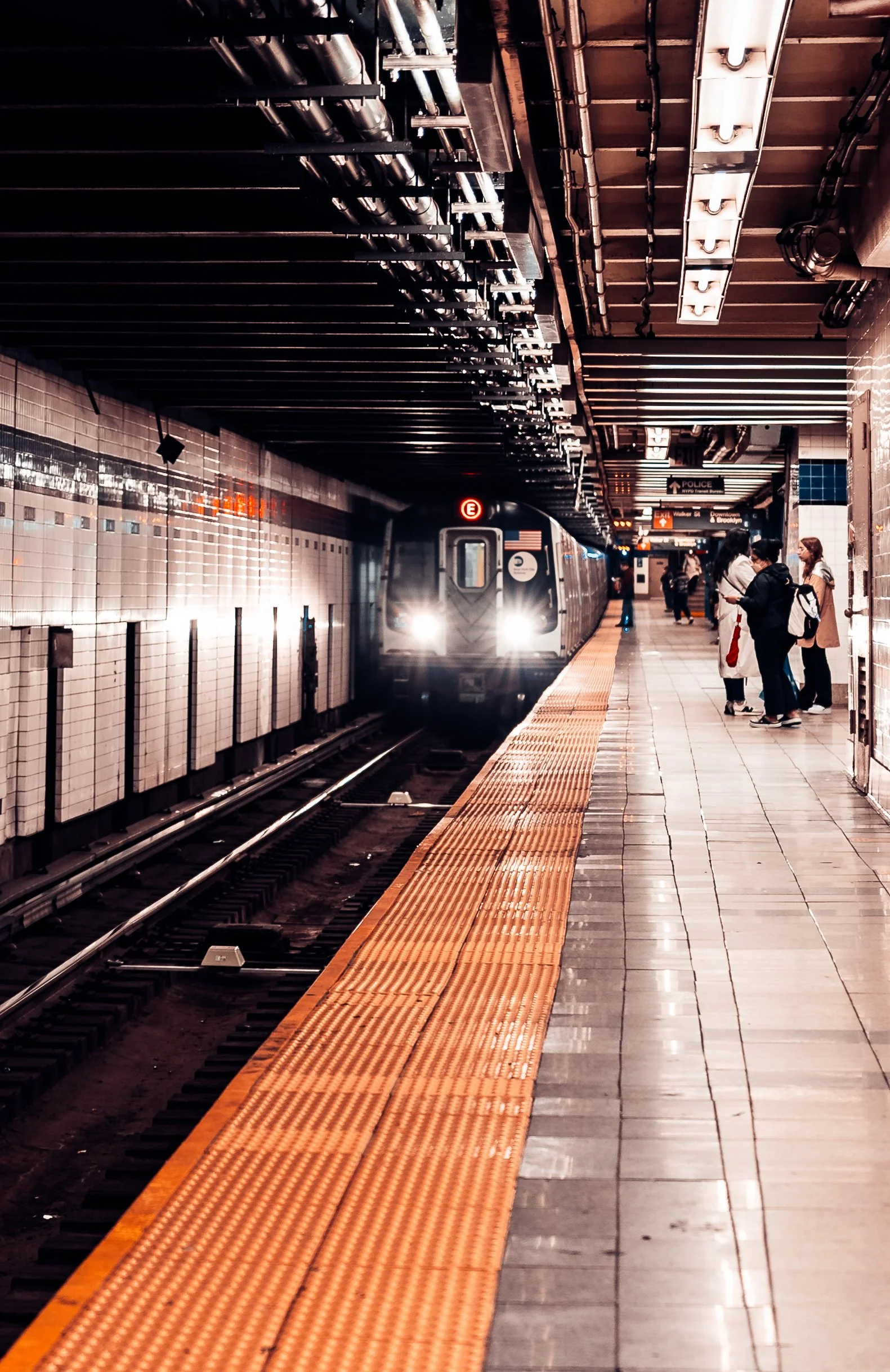 Subway train arriving at an underground station platform with passengers waiting.