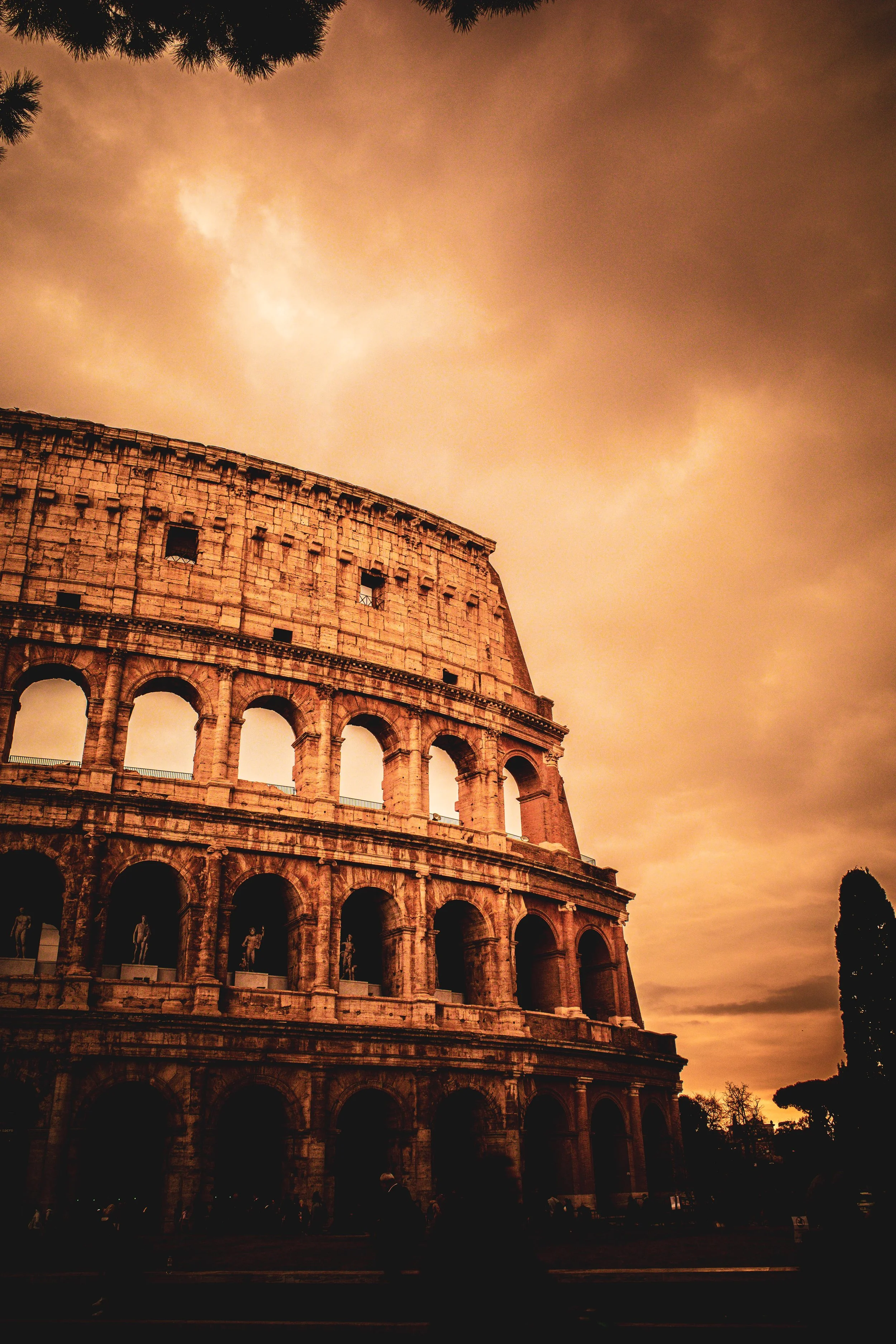 The Colosseum in Rome during sunset with dark clouds in the sky.