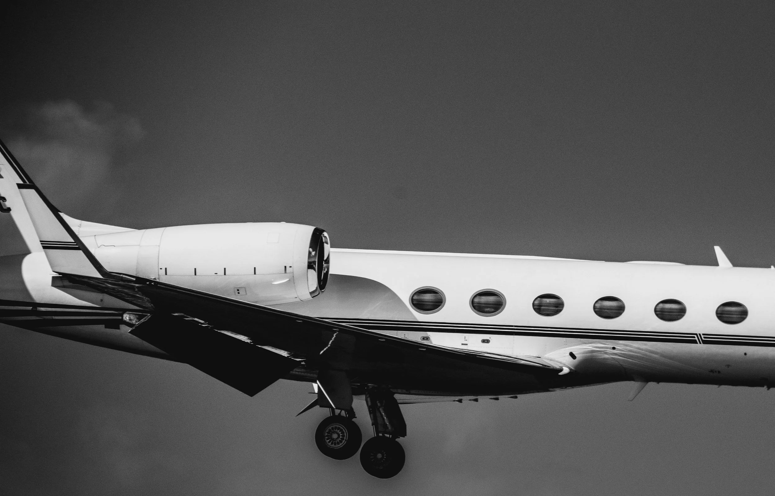 Close-up of an airplane's front section, focusing on the landing gear and engine, with a dark sky background.