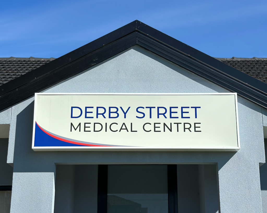 Sign for Derby Street Medical Centre on the exterior of a light blue building.