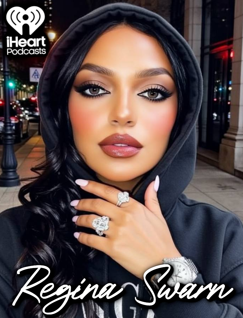 A woman with long black hair, makeup, and lip gloss, wearing a black hoodie, showing off diamond rings and a watch, standing on a city street at night with blurred lights and buildings in the background.