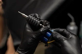 Close-up of a tattoo artist tattooing the skin with a tattoo machine.