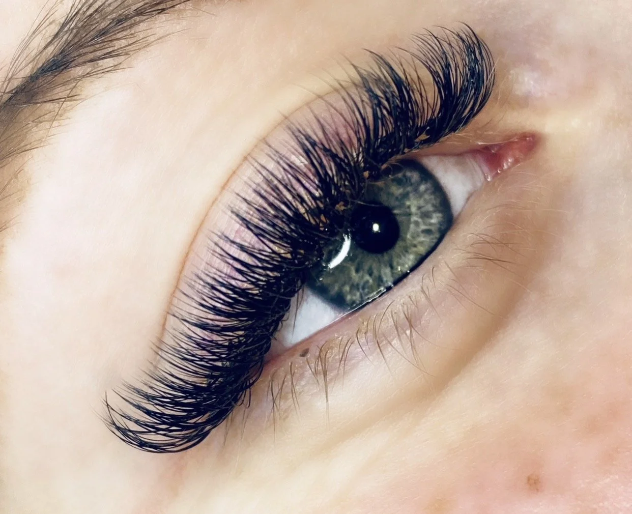 A close-up of a person's eye with long, thick, signature style of eyelash extensions from studio 17 artistry