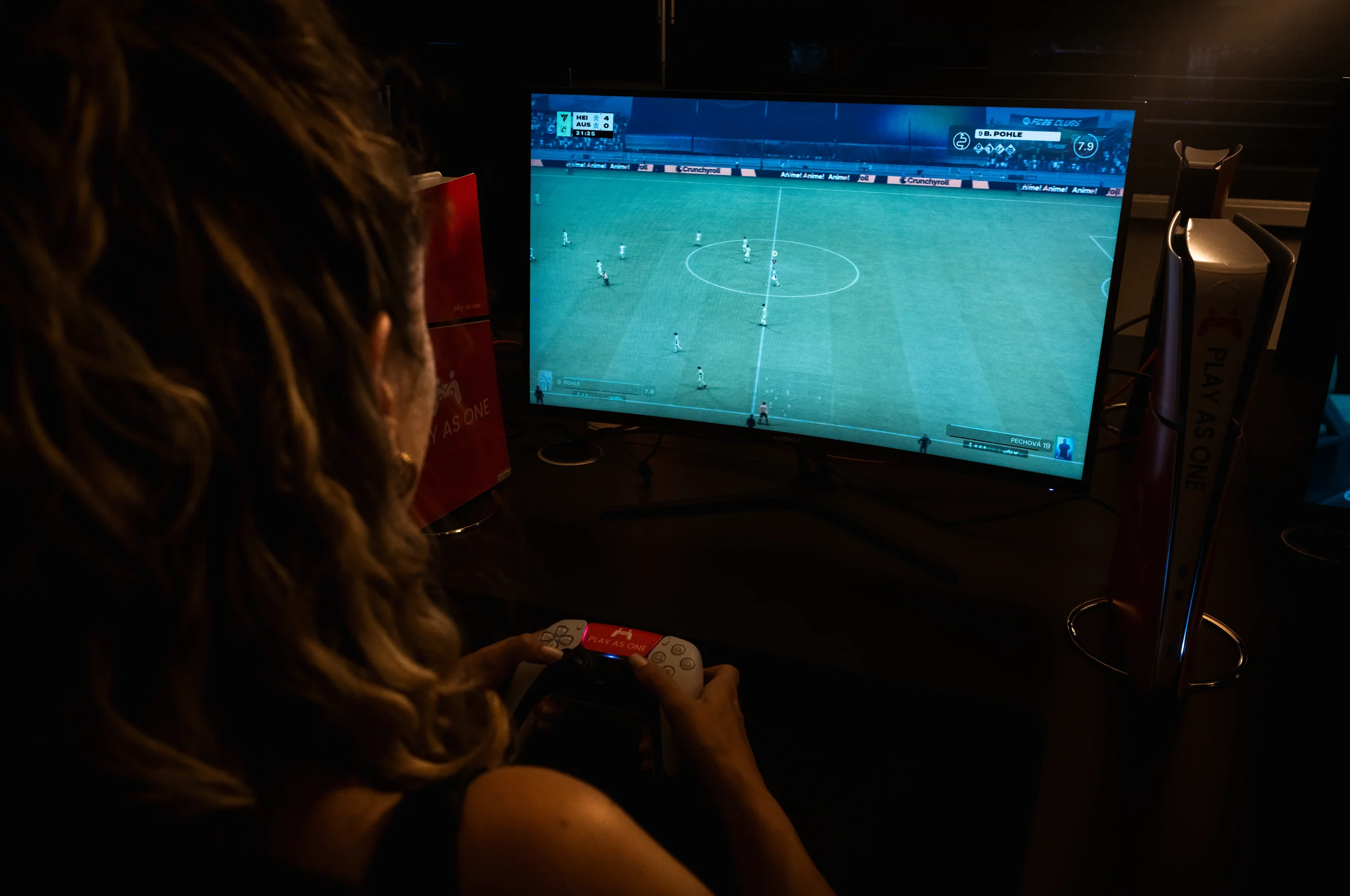 Person spielt ein E-Sport-Spiel auf einem Bildschirm, während sie einen Controller hält, in einem dunklen Raum.