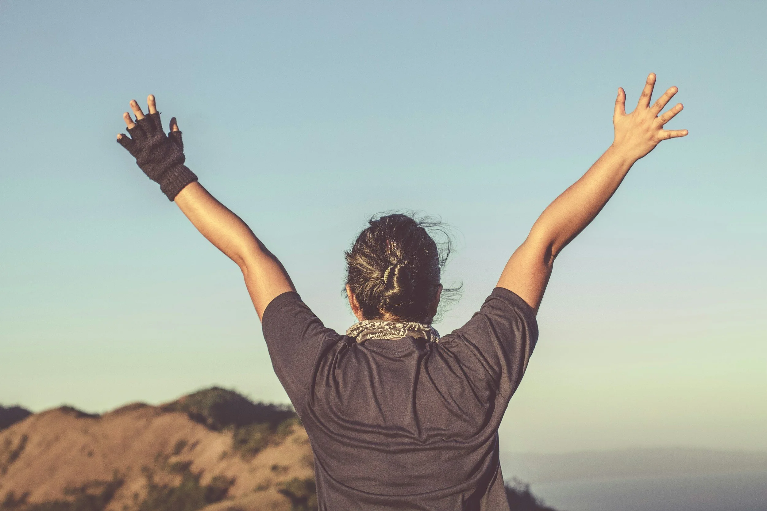Woman at the top of a mountain with her arms up