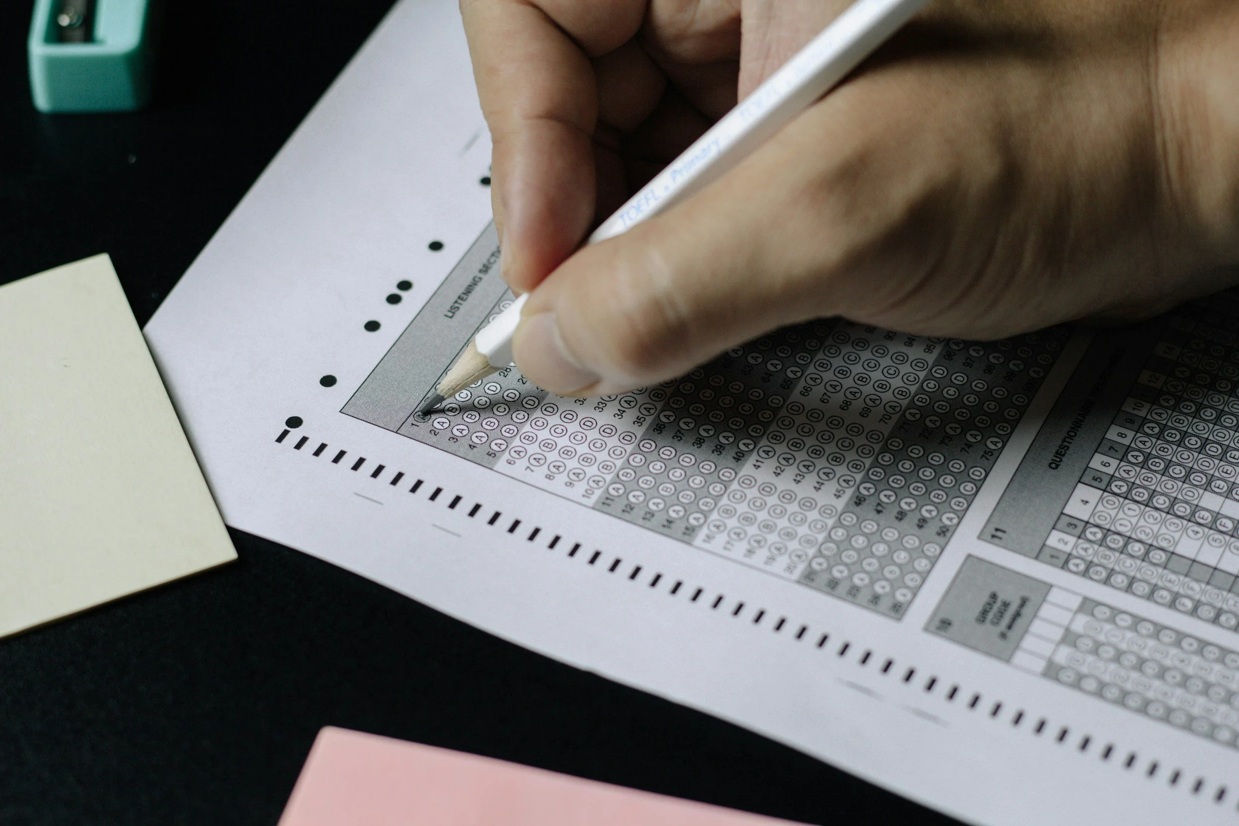 Hand holding a white pencil filling out a scantron personality test