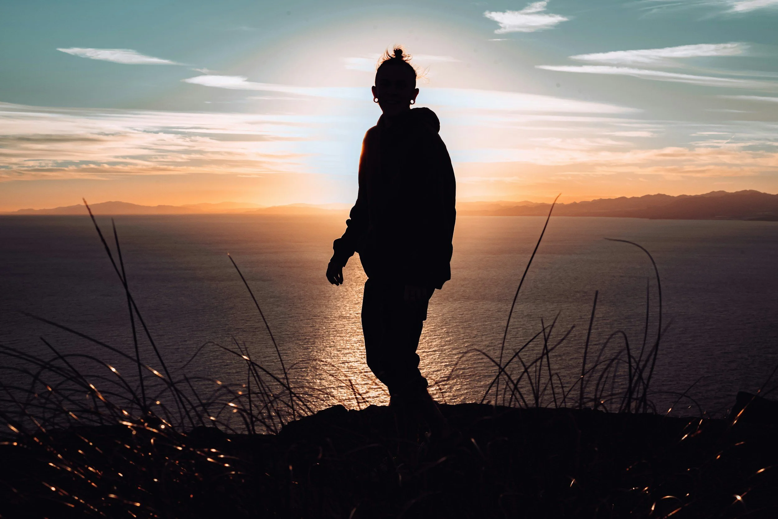 women standing in front of a sunset