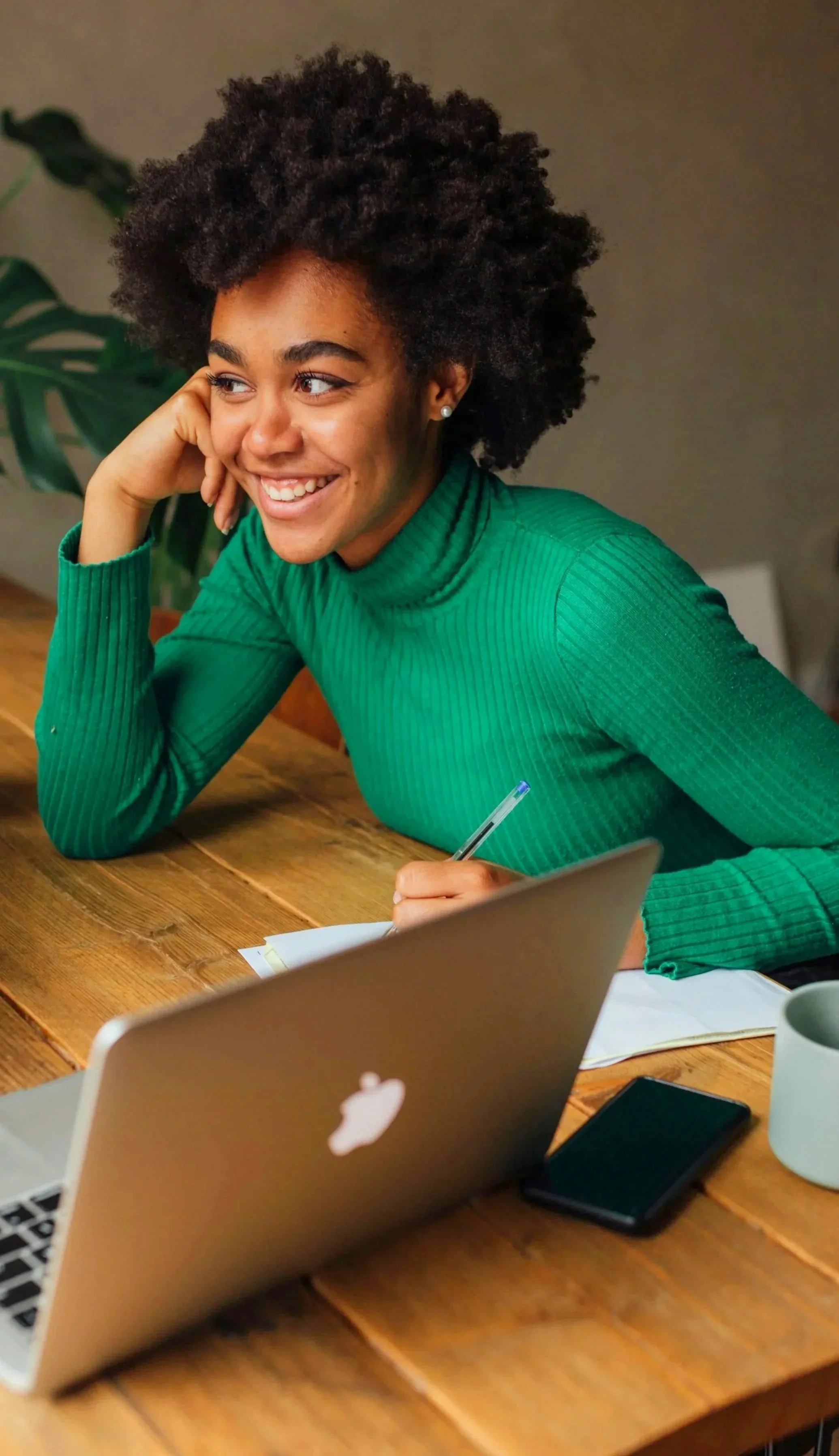 Photo of woman smiling, siting at desk with notebook