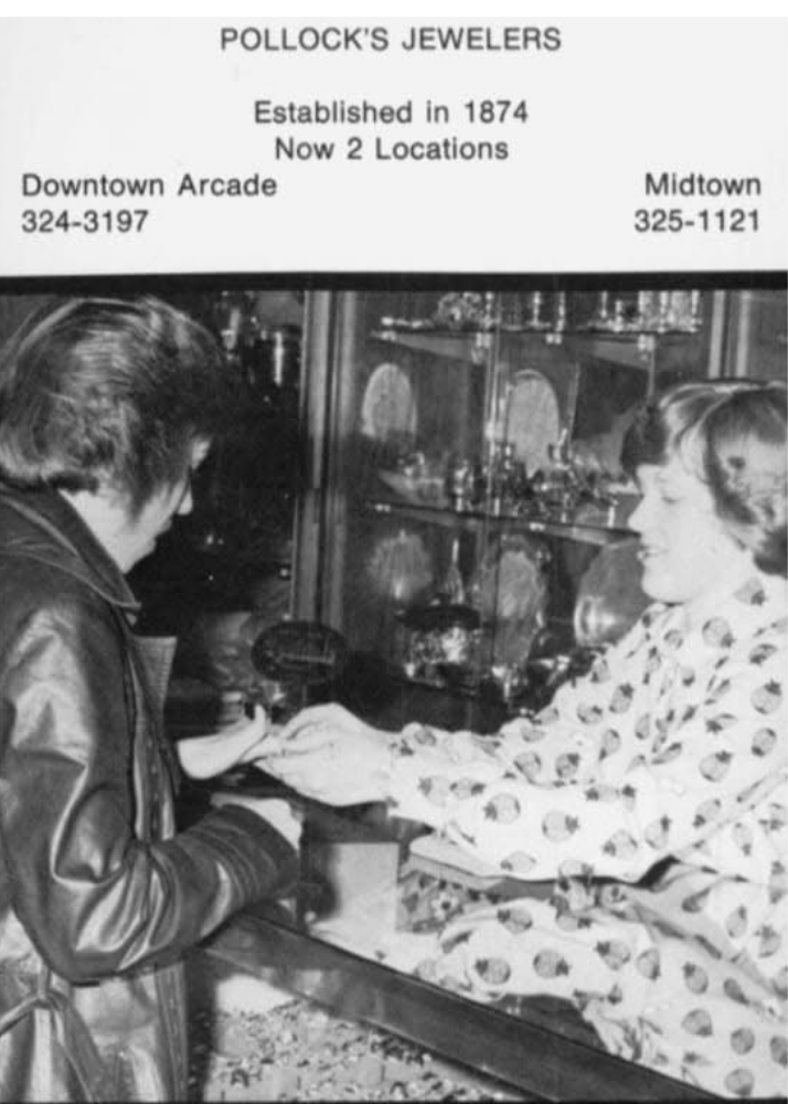 A black and white photo of a woman in a polka dot dress handing jewelry to a man at Pollock's Jewelers, established in 1874, with two store locations: Downtown Arcade and Midtown.