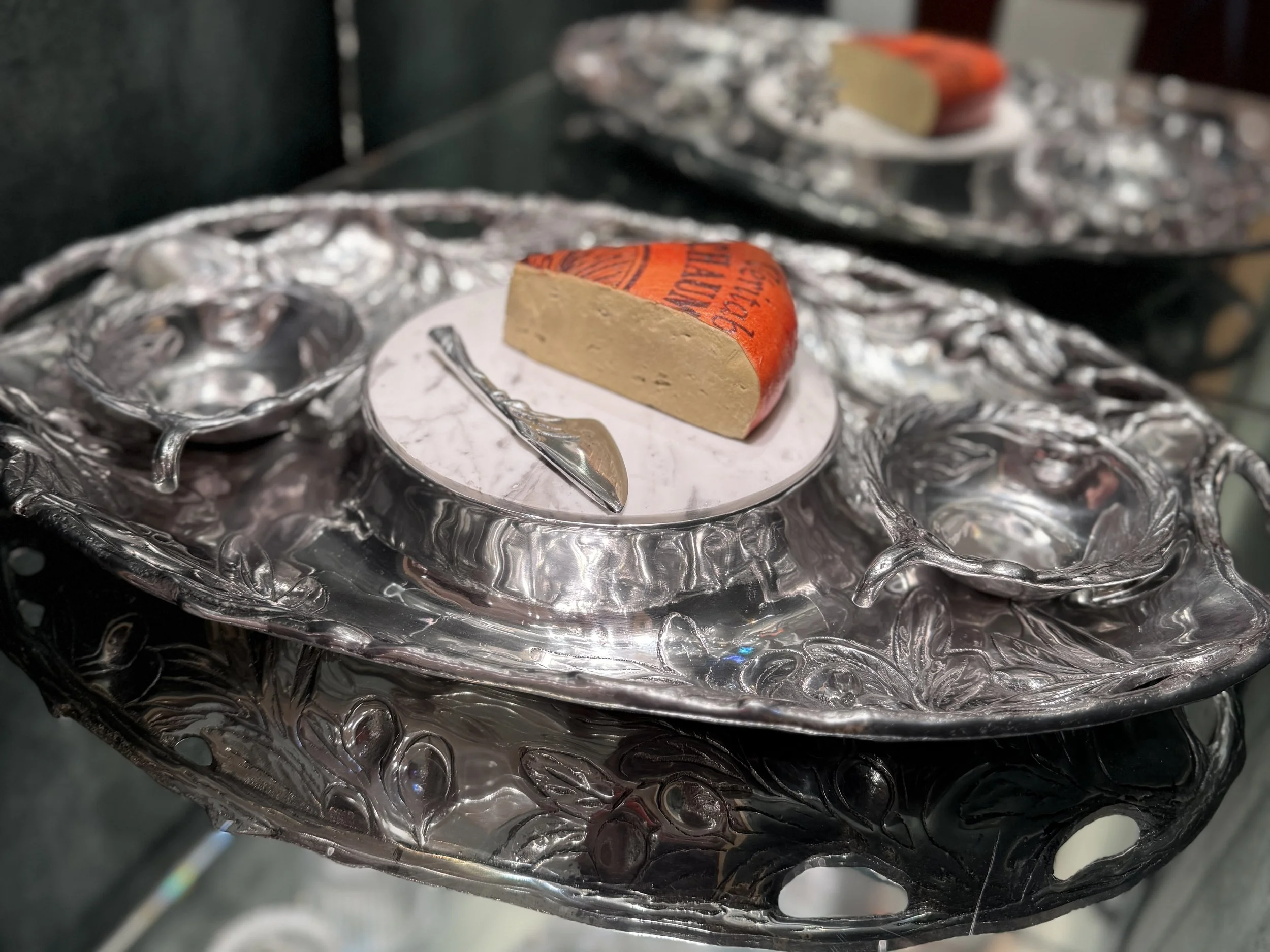 A piece of cheese with orange packaging resting on a silver decorative tray.