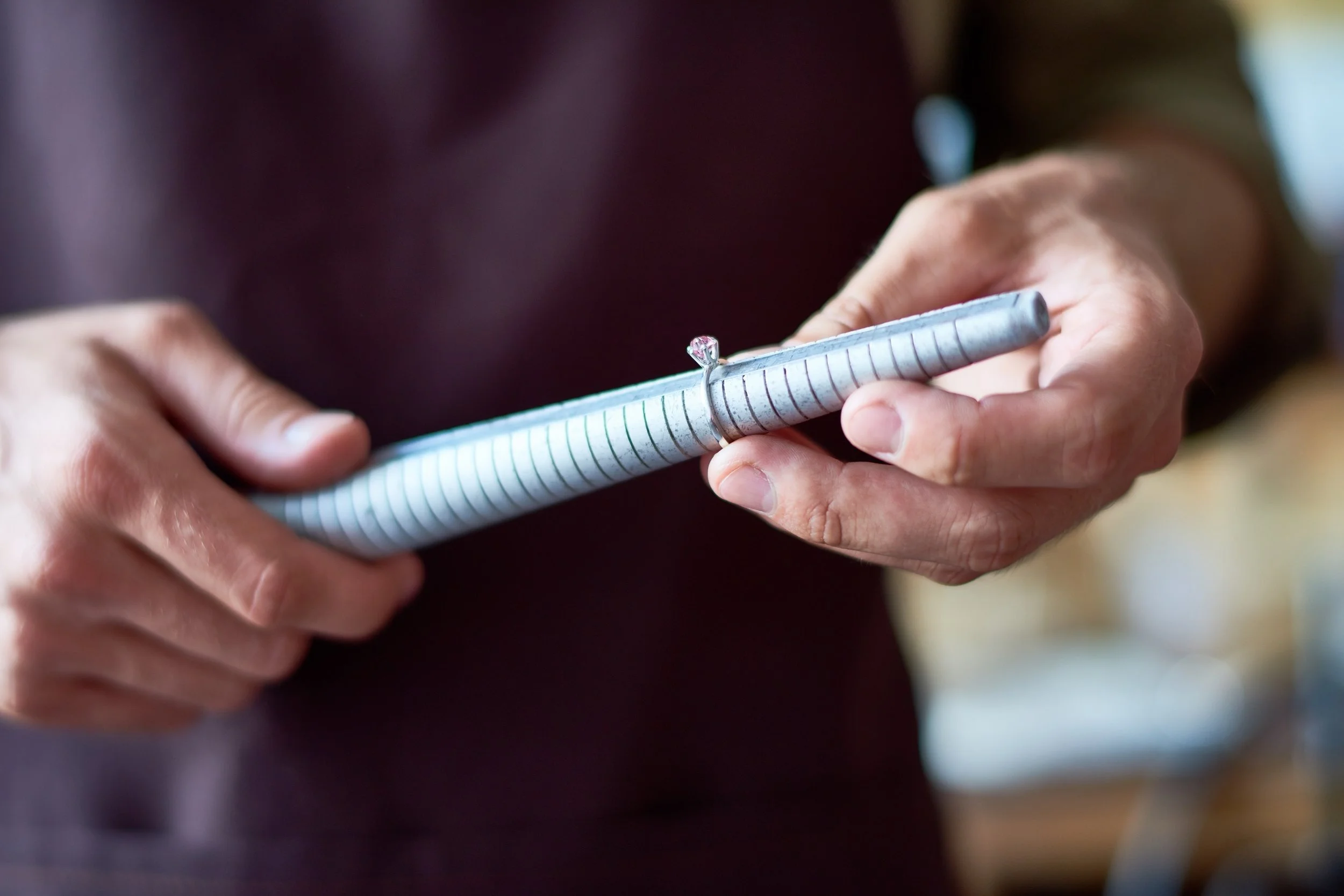Person holding a silver ring with a large gemstone over a blue and white spiral notebook.