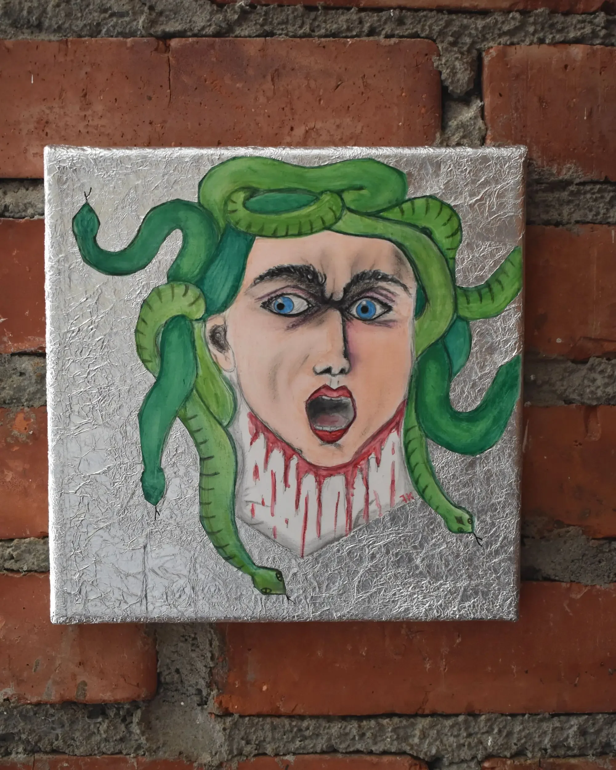 Full view of Medusa. Mirror of Reflections., a contemporary artwork by Francesca V Kranz, displaying the square painting on a brick wall to emphasize the textured aluminum background and the tragic expression.