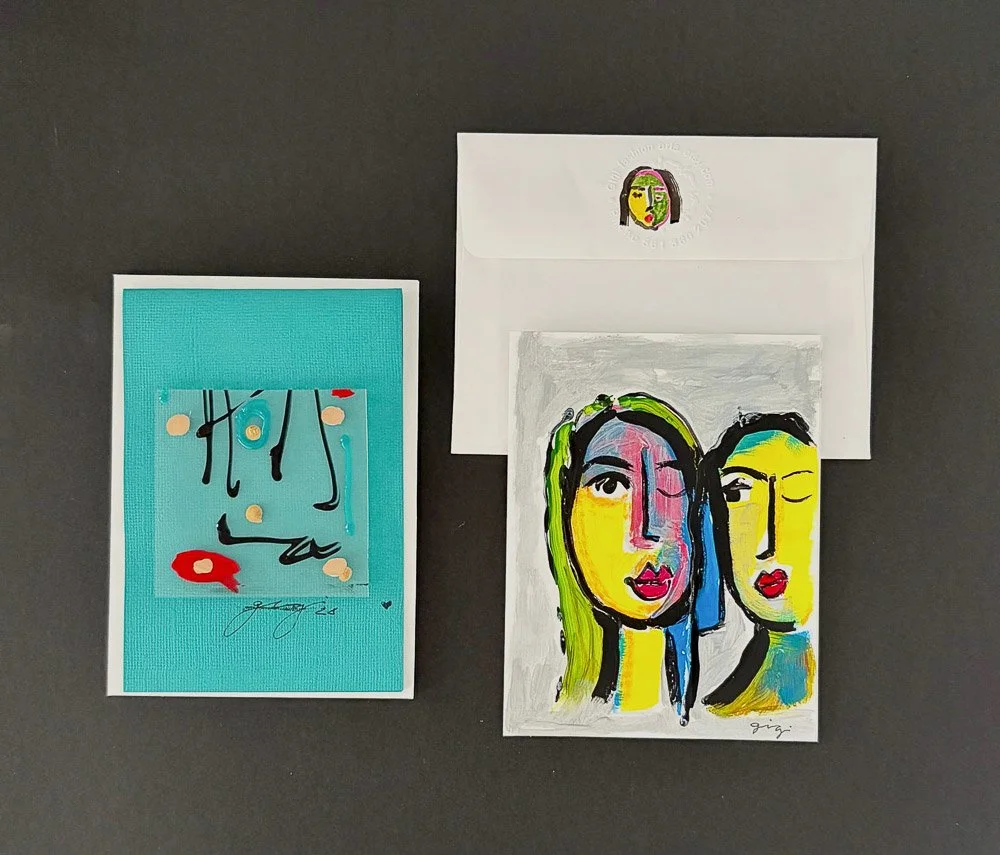 Colorful abstract art pieces, one featuring two stylized female faces with vibrant colors and bold brush strokes, another with a minimalist style on a turquoise background, and an envelope with a small sticker of a colorful face.