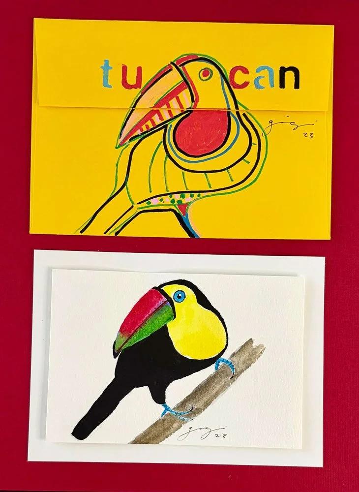 Colorful drawing of a toucan bird with a large, multicolored beak, yellow face, and black body, perched on a branch. The artwork appears to be created with markers or paint.