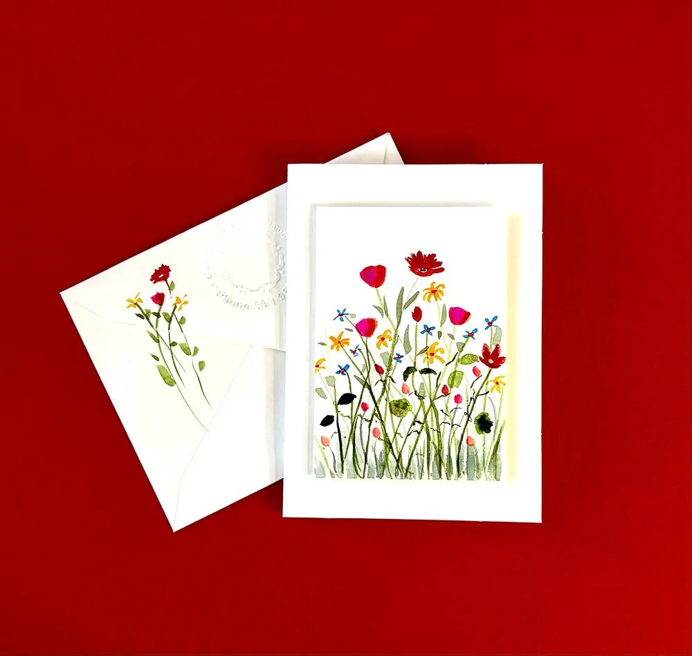 A greeting card with a colorful flower illustration and matching envelope on a red background.