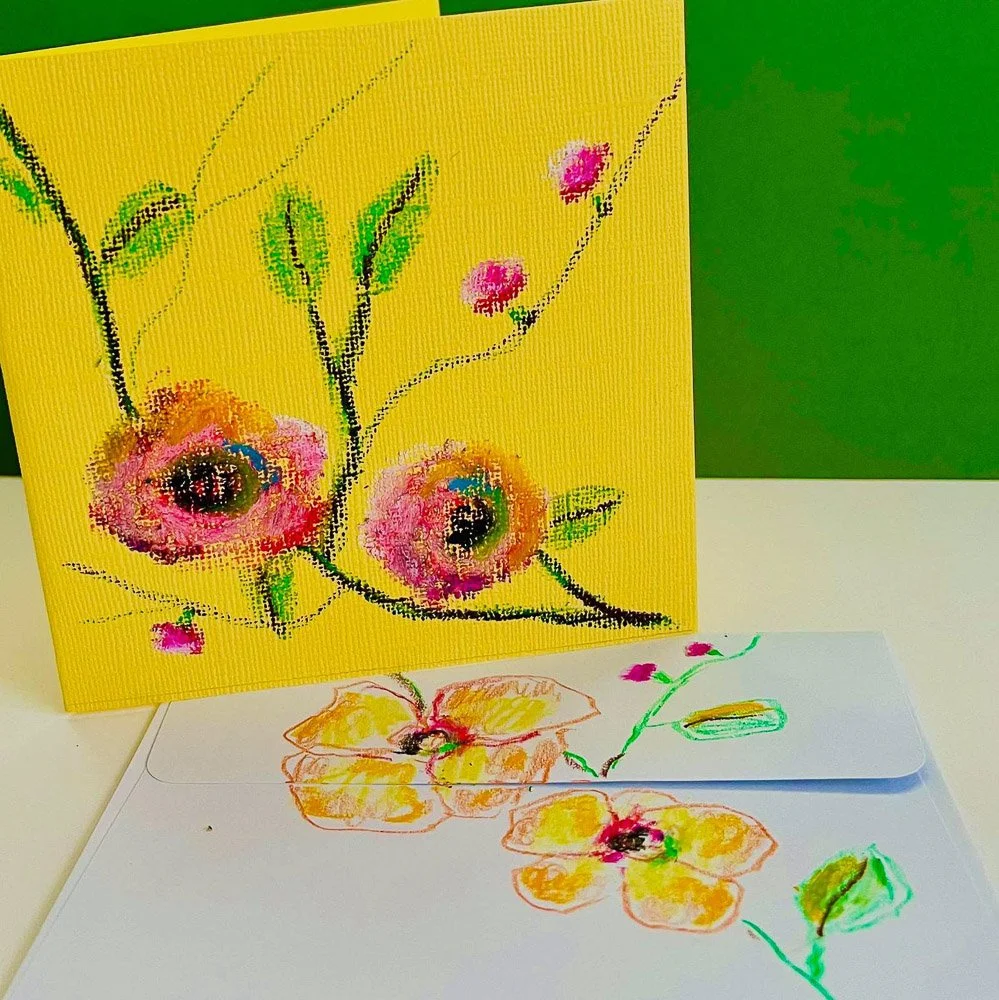 Colorful handmade flower paintings on yellow canvas and white paper, featuring pink, yellow, green, and black accents.